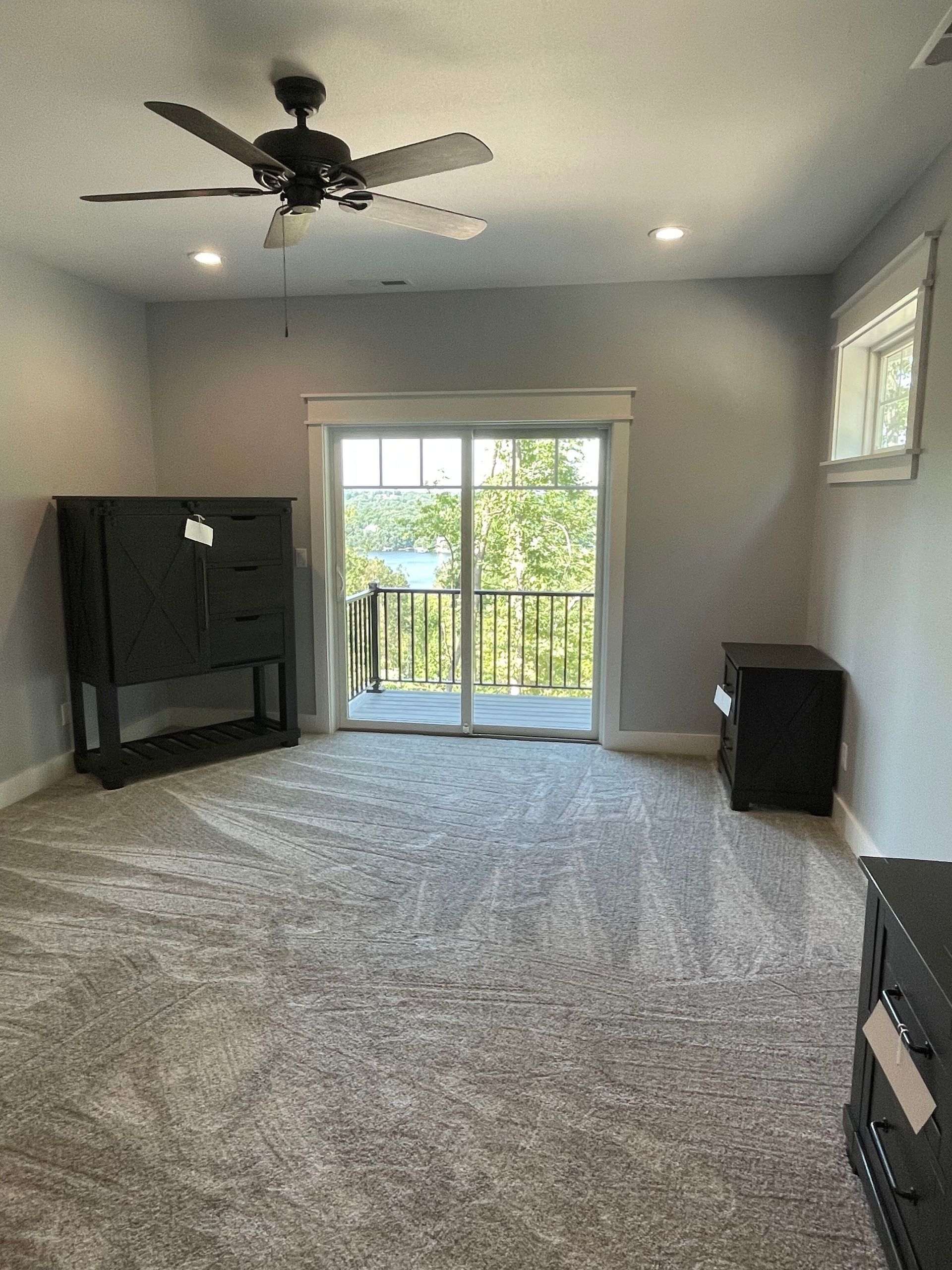Empty carpeted living room with ceiling fan, fireplace, and sliding glass doors to a balcony.