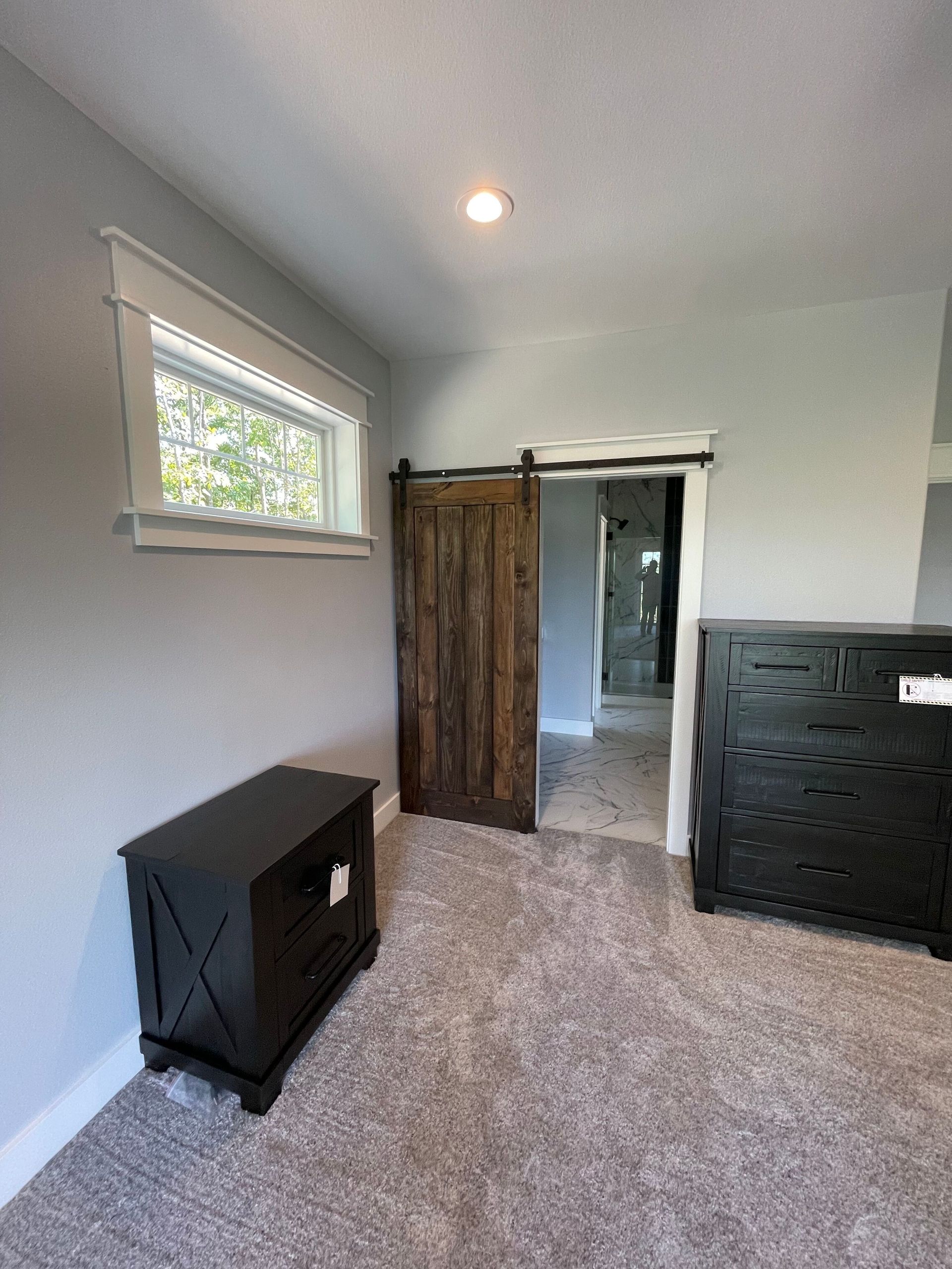 Small bedroom with gray walls, carpet, window, dresser, and an open closet door.