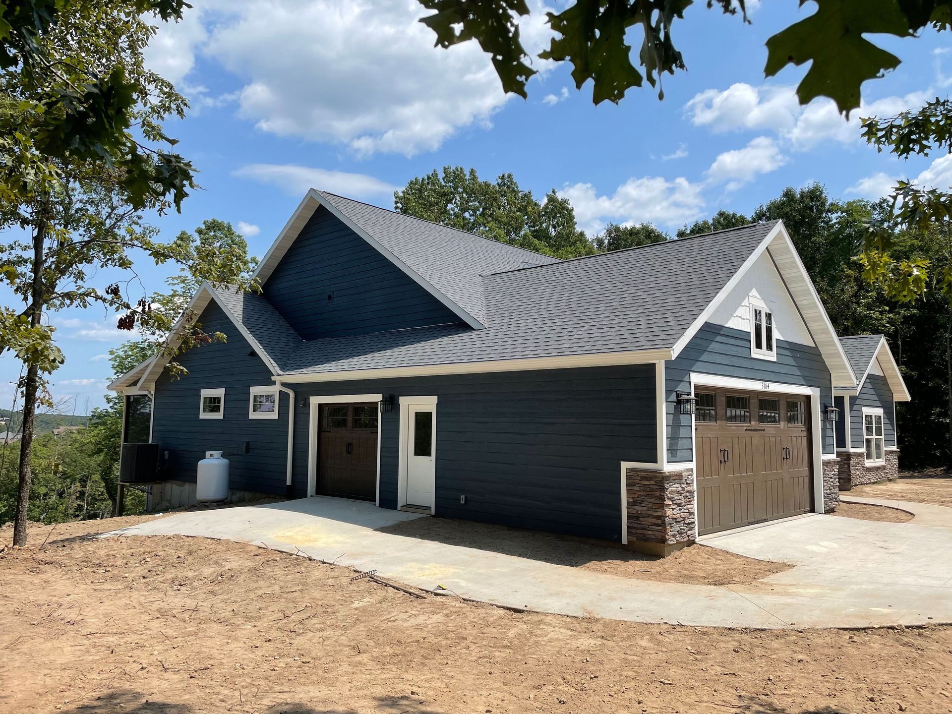 New dark-blue house under construction with white trim and a two-car garage, viewed from the front.