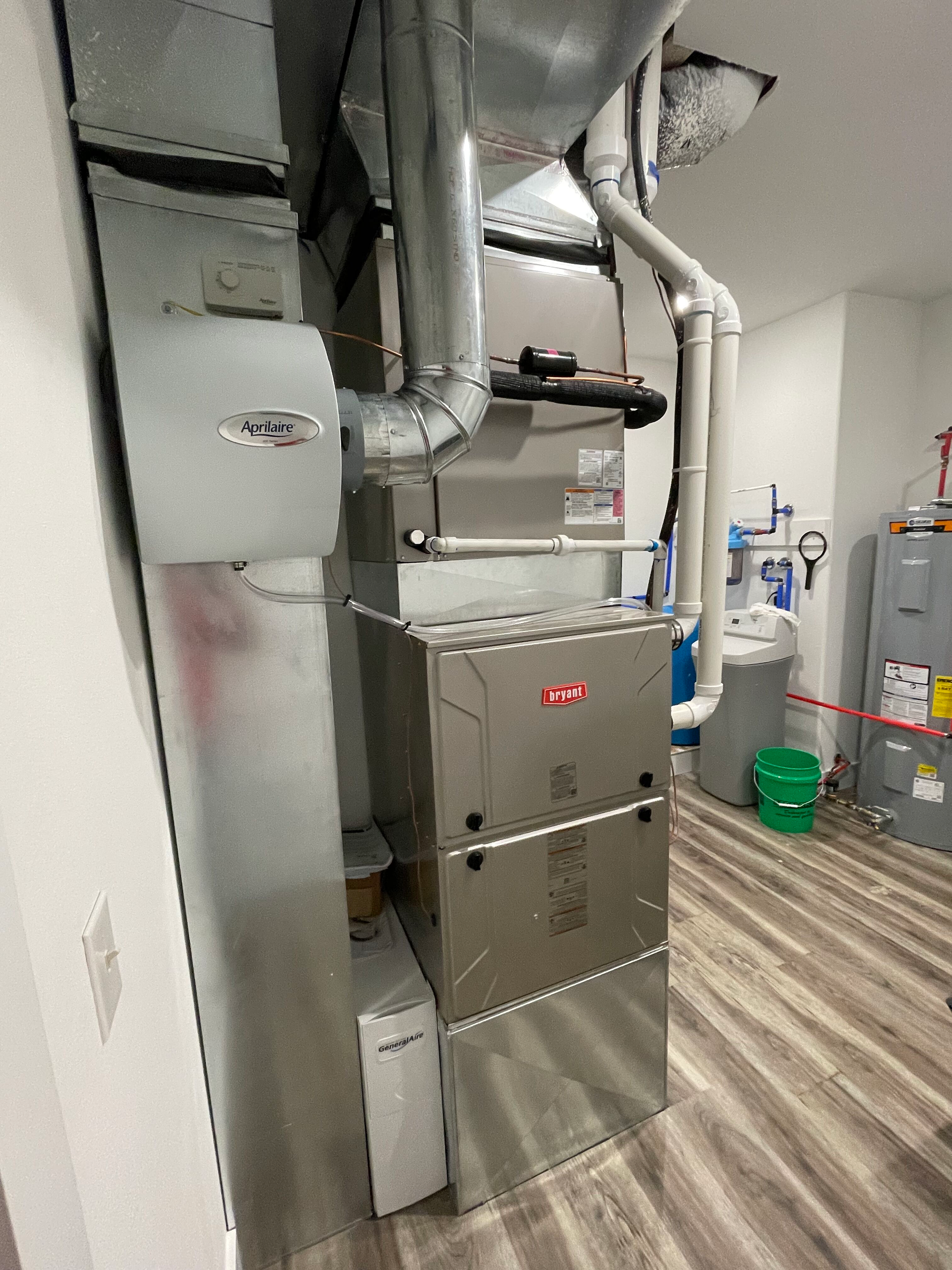 Basement utility room with furnace, ducts, water heater, and storage bins on wood-look flooring