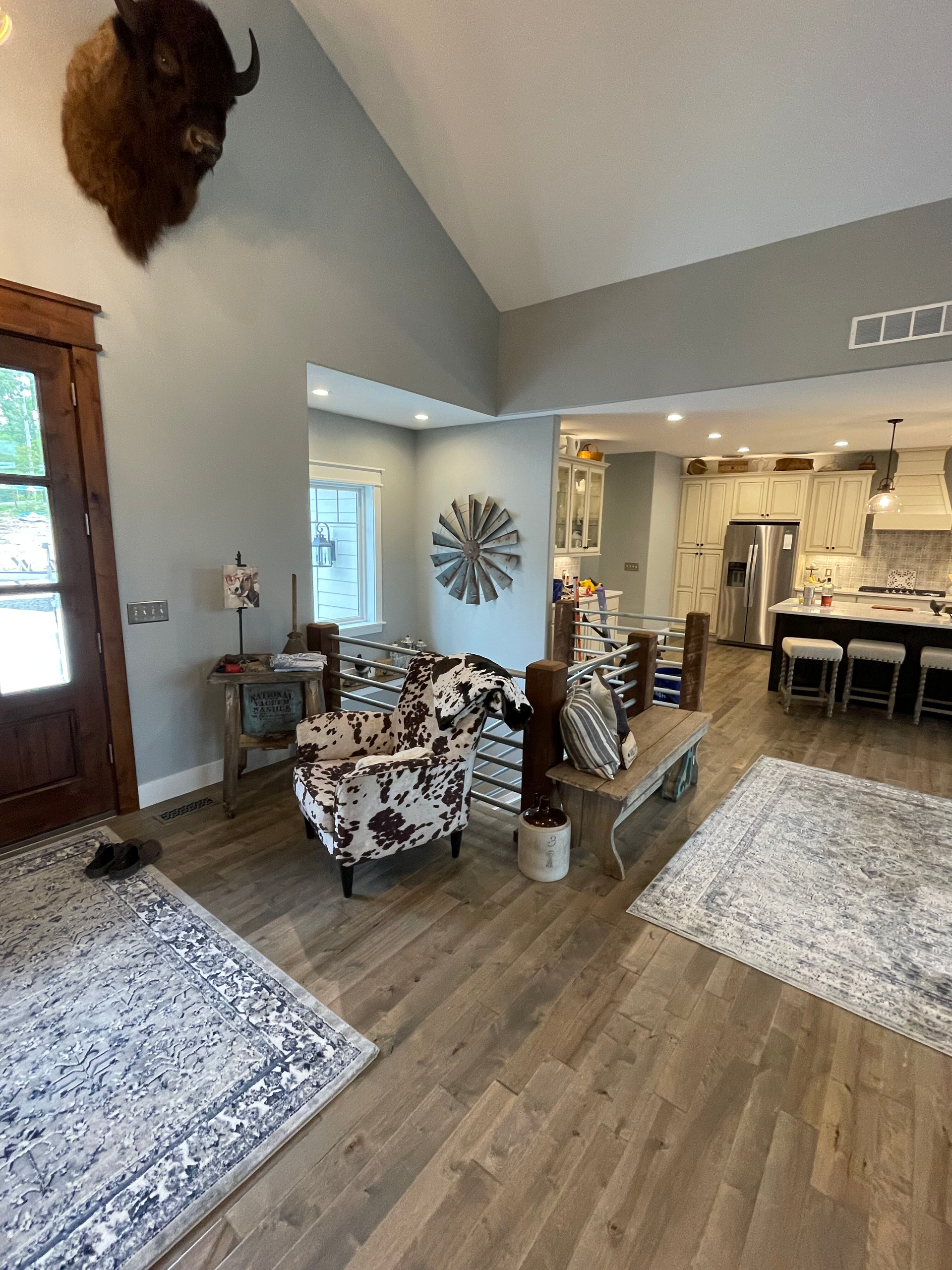 Modern open-concept living room with patterned chairs, hardwood floor, and kitchen in the background