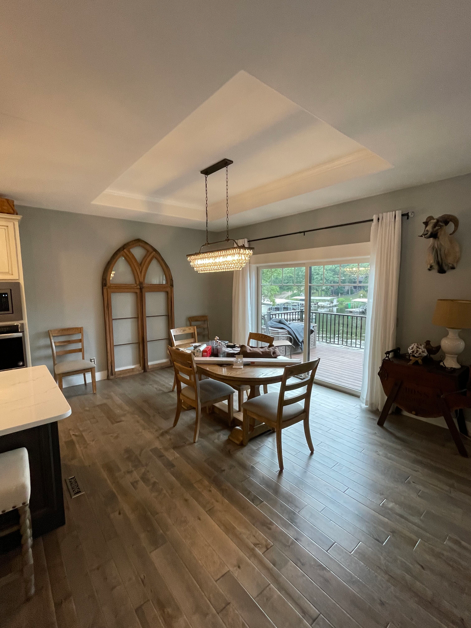 Bright dining room with wooden table, chandelier, sliding glass door, and warm wood flooring.
