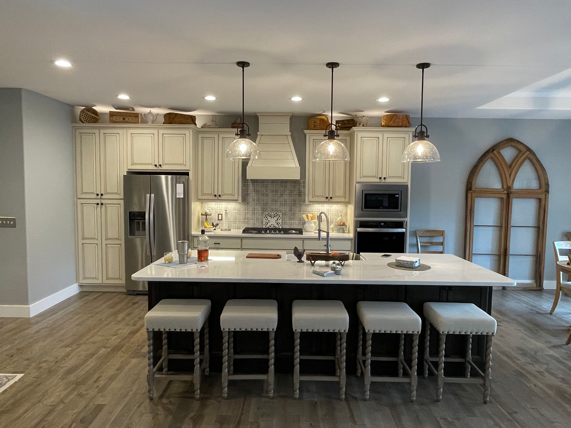 Modern kitchen with white cabinets, stainless steel appliances, island seating, and arched wall decor.