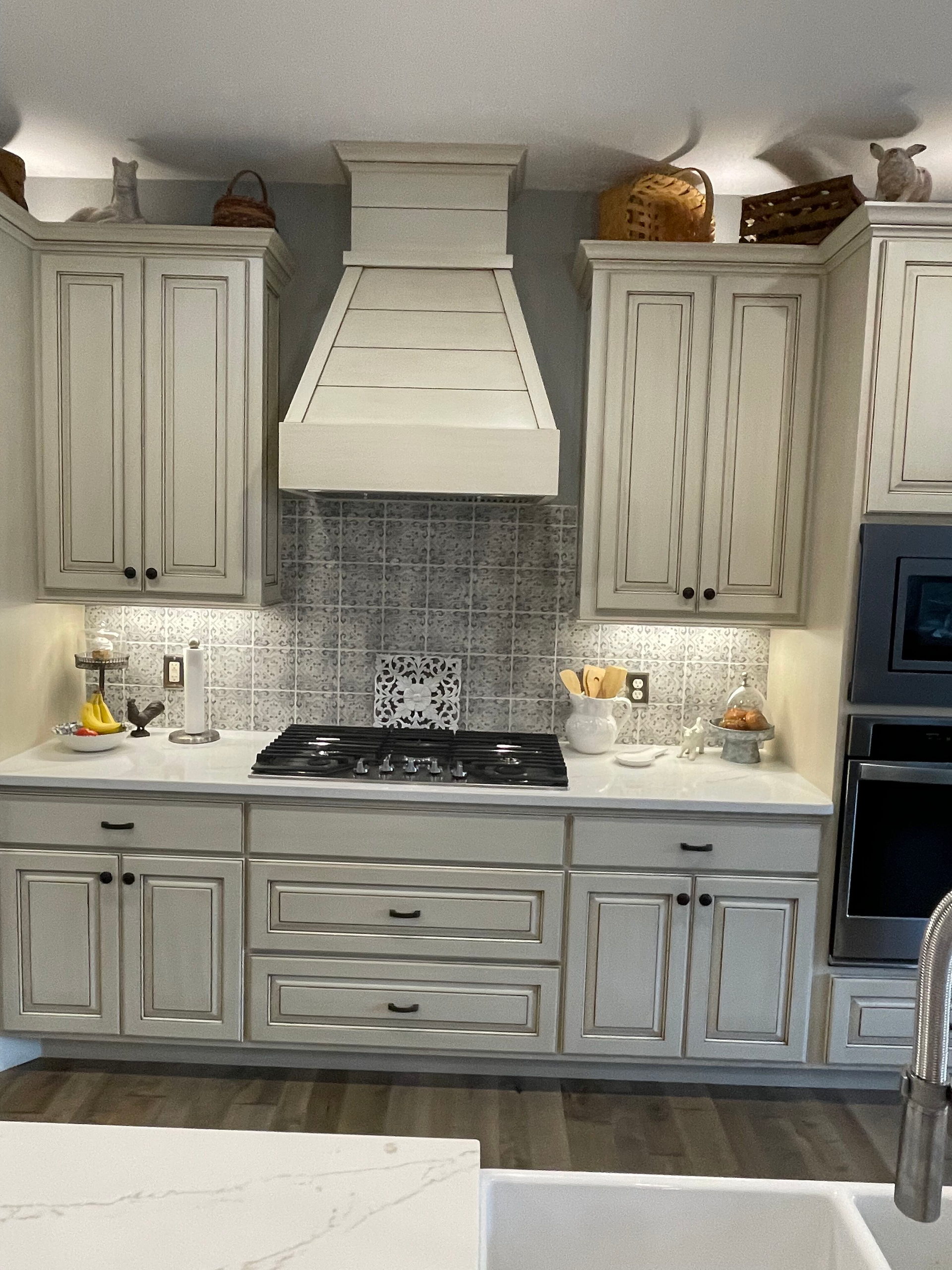 White kitchen with cabinets, central range hood, stove, and marble backsplash visible.