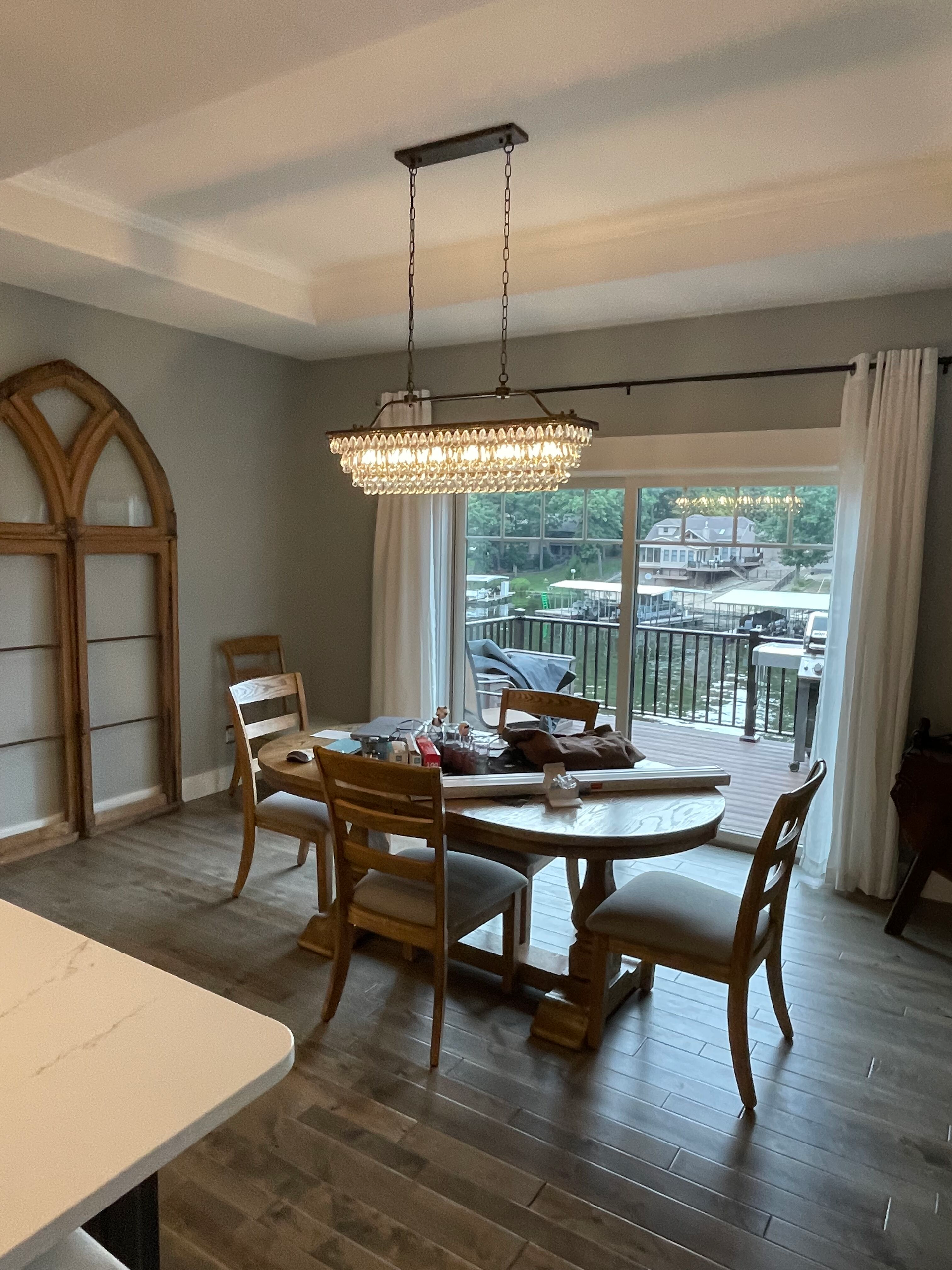 Dining room with round table, crystal chandelier, wood chairs, and sliding doors to a patio.
