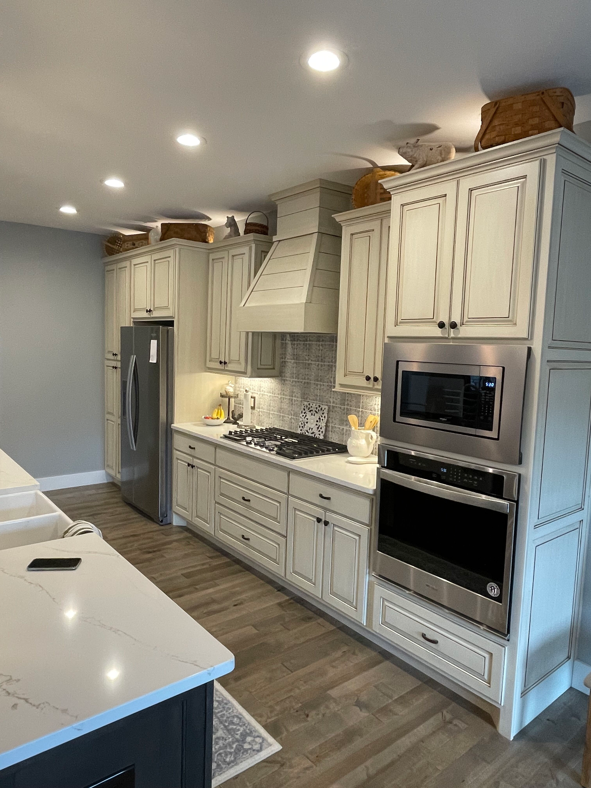 Bright white kitchen with marble countertops, stainless appliances, and a large island under recessed lights