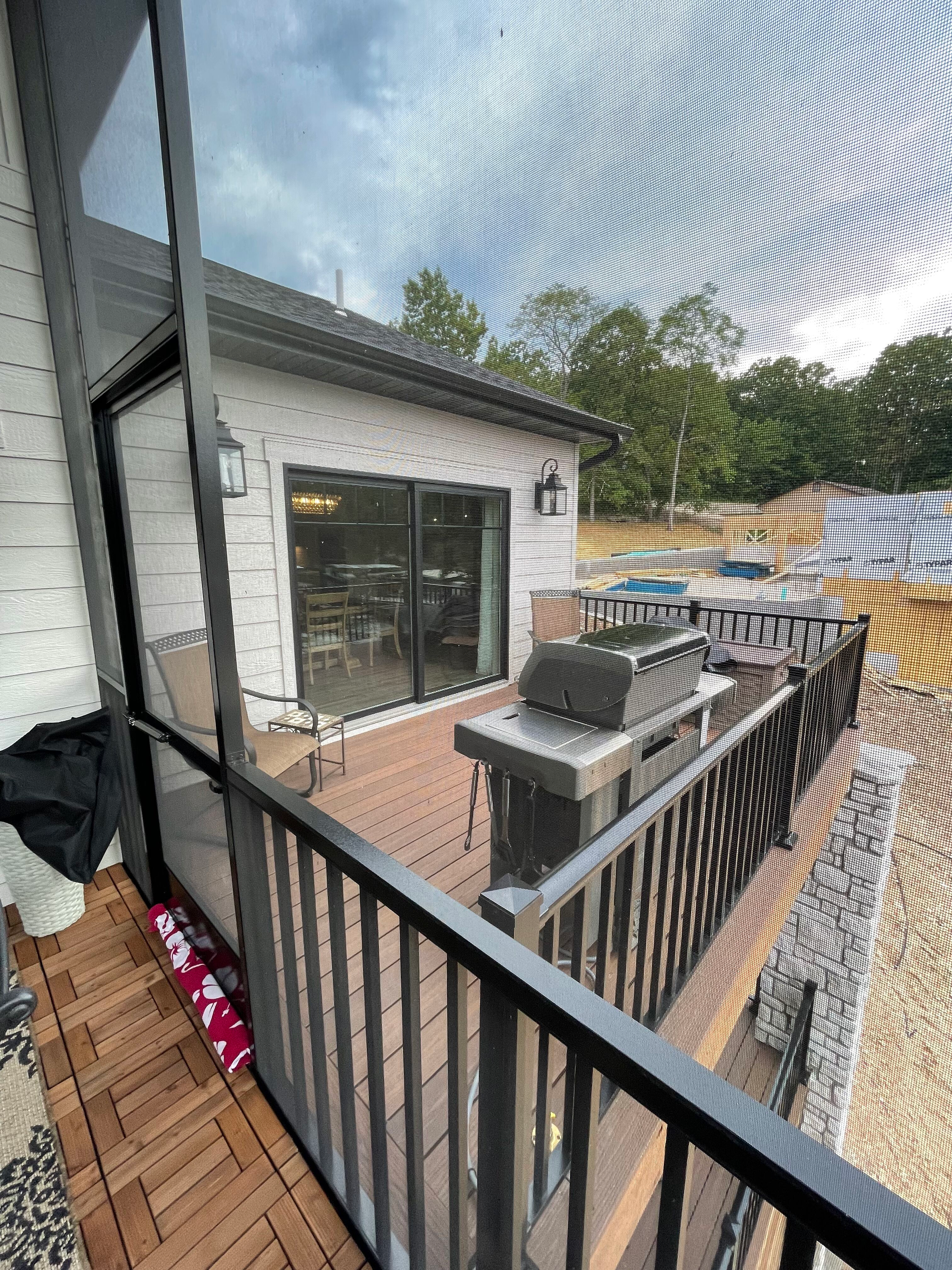 Small balcony with black railing, brick pavers, grill, patio furniture, and a white house exterior.