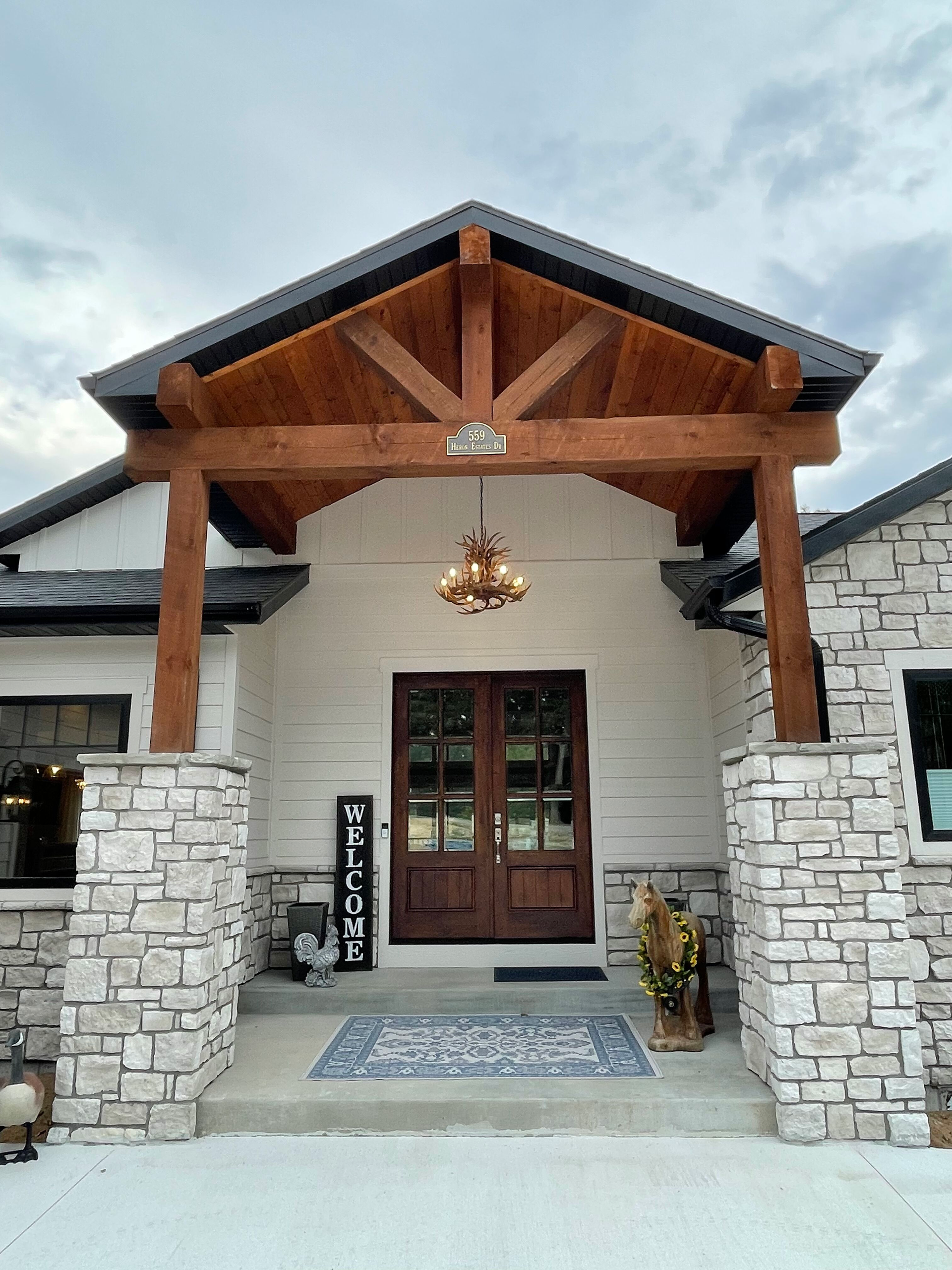 Stone-front house entry with wooden gabled porch, hanging lantern, and double doors