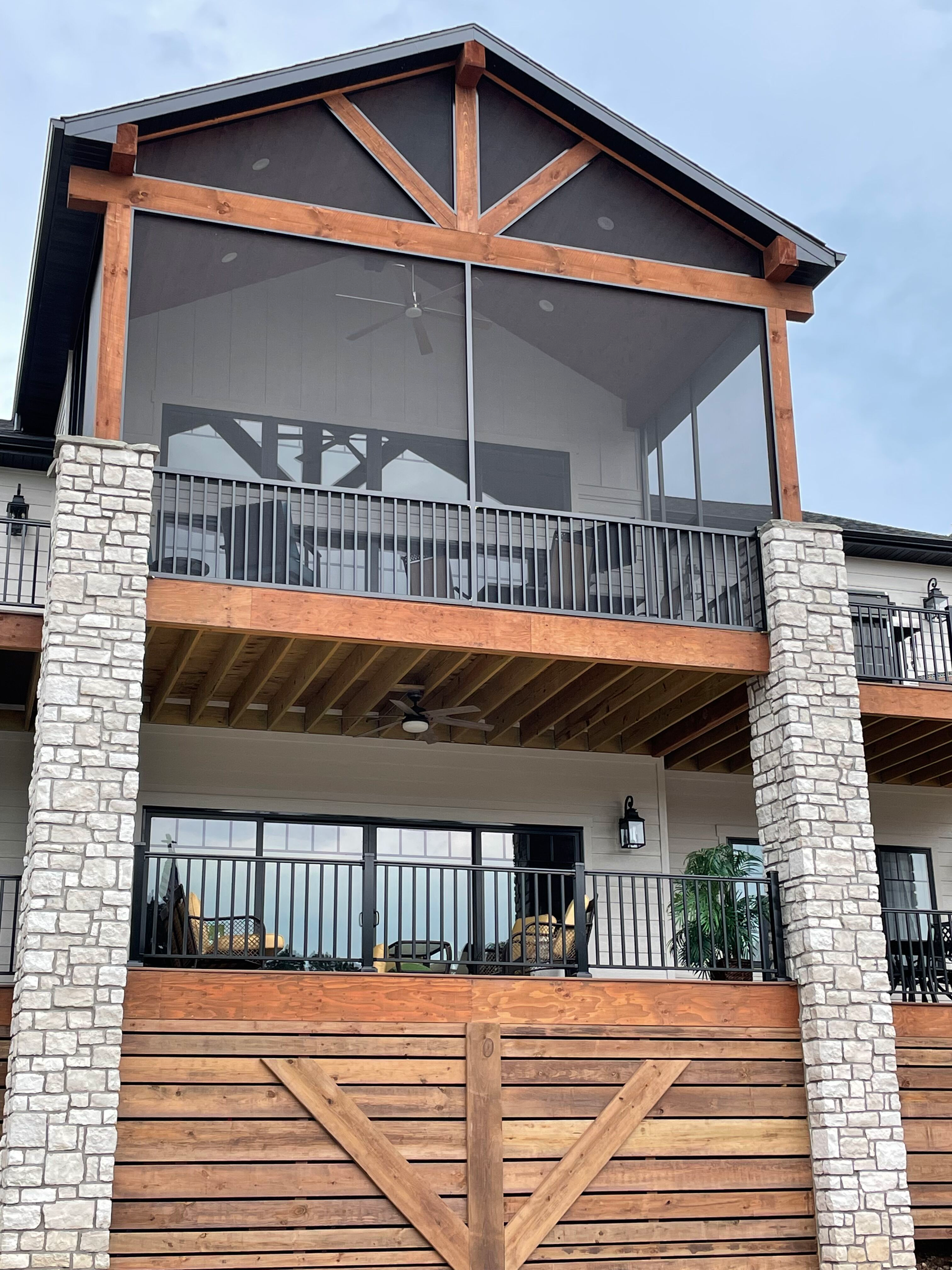 Three-story stone and wood house exterior with balcony and large windows