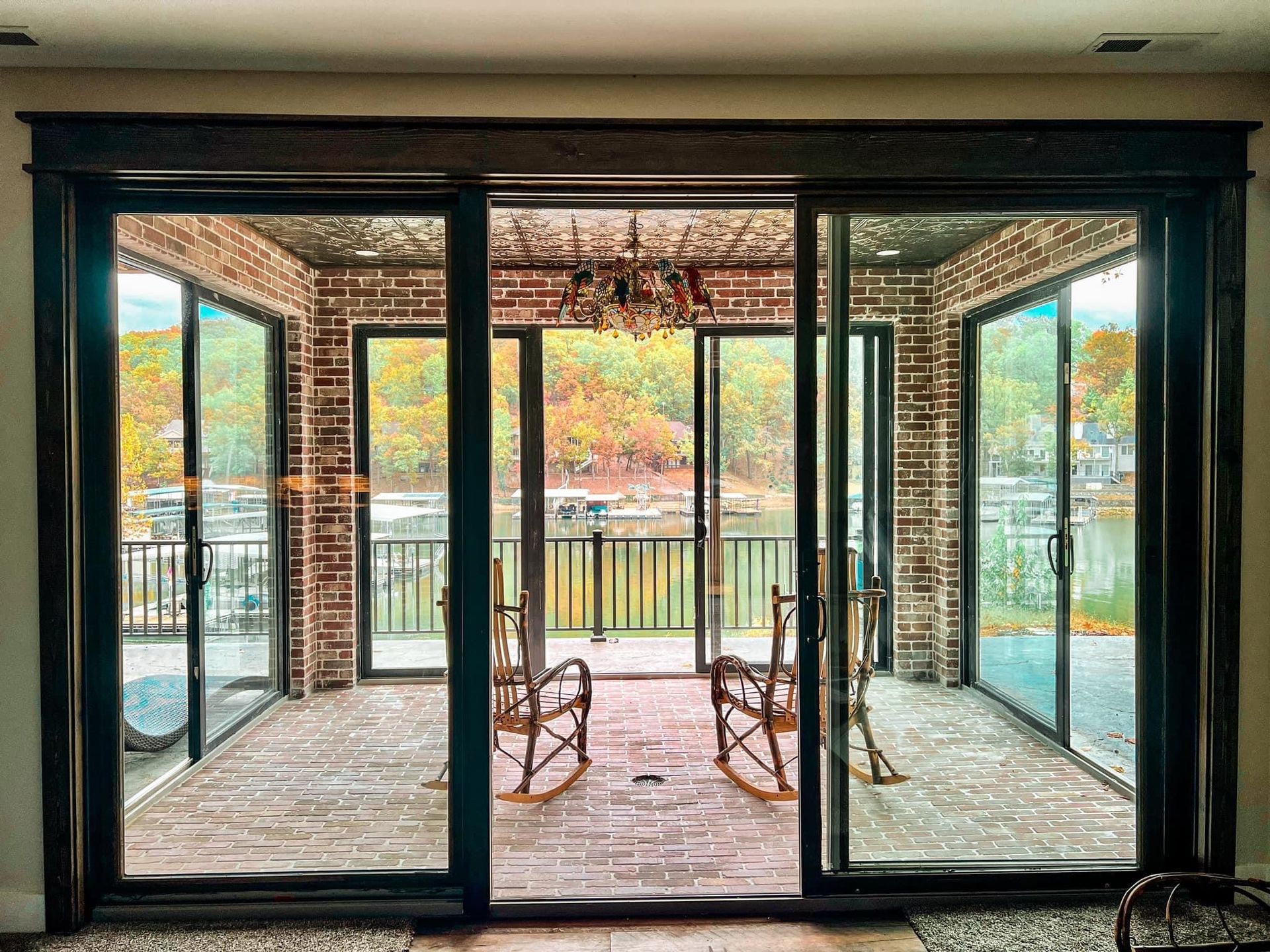 Sliding glass doors open to a covered patio with chairs and a view of trees and water.