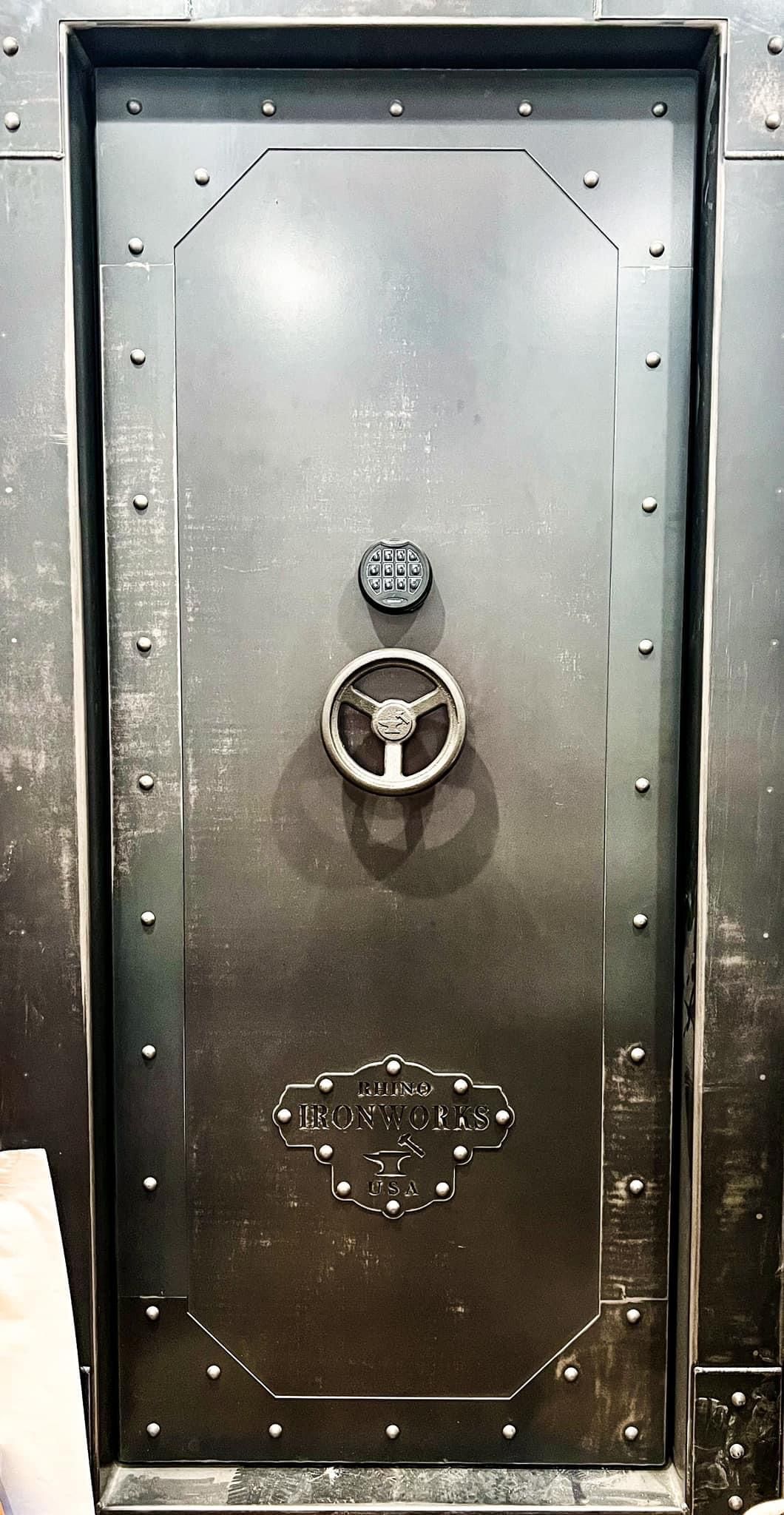 Industrial metal vault door with a wheel handle and riveted frame