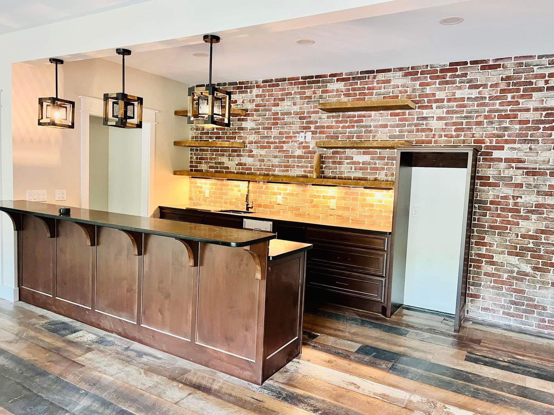 Rustic bar with wood counter, brick wall, hanging lights, and exposed wood beam ceiling
