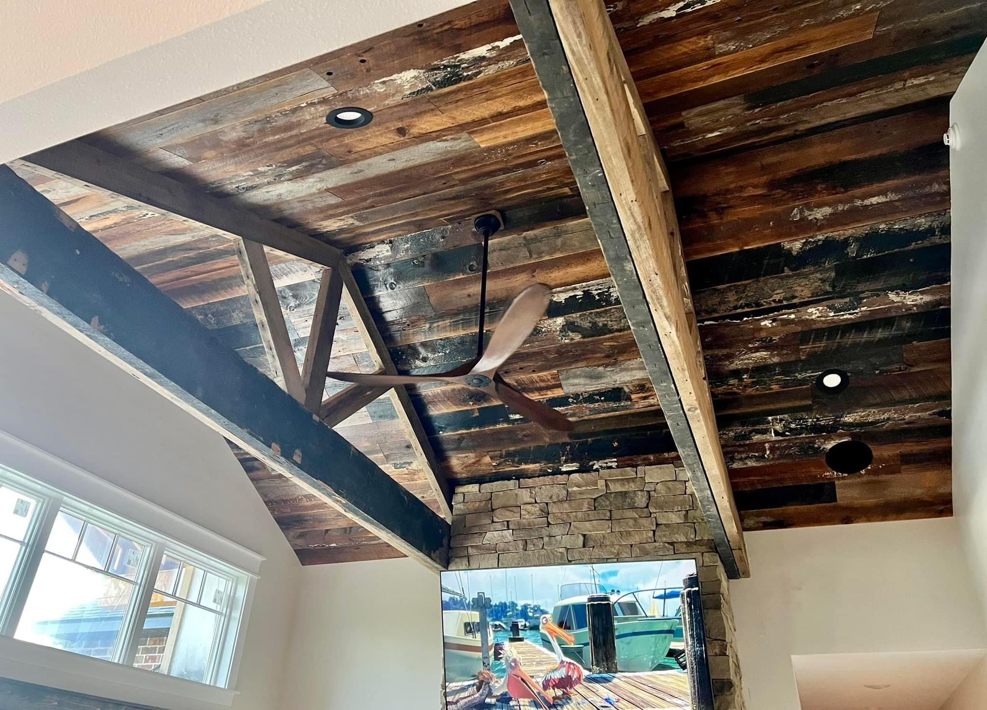 Rustic wooden ceiling beams above a bright room with a window and hanging light fixtures