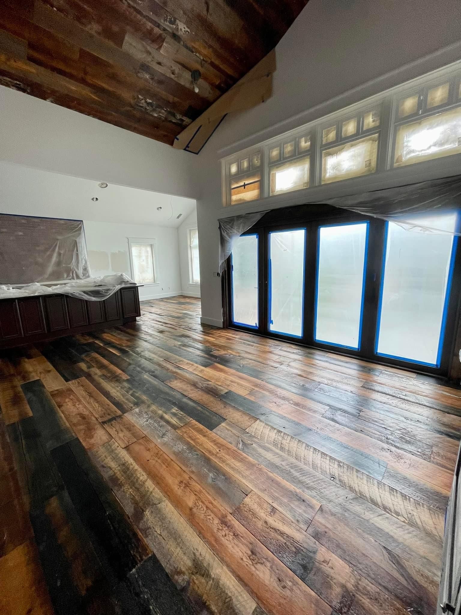 Spacious room with dark wood floors, vaulted ceiling, and large sliding glass doors opening to a bright snowy view