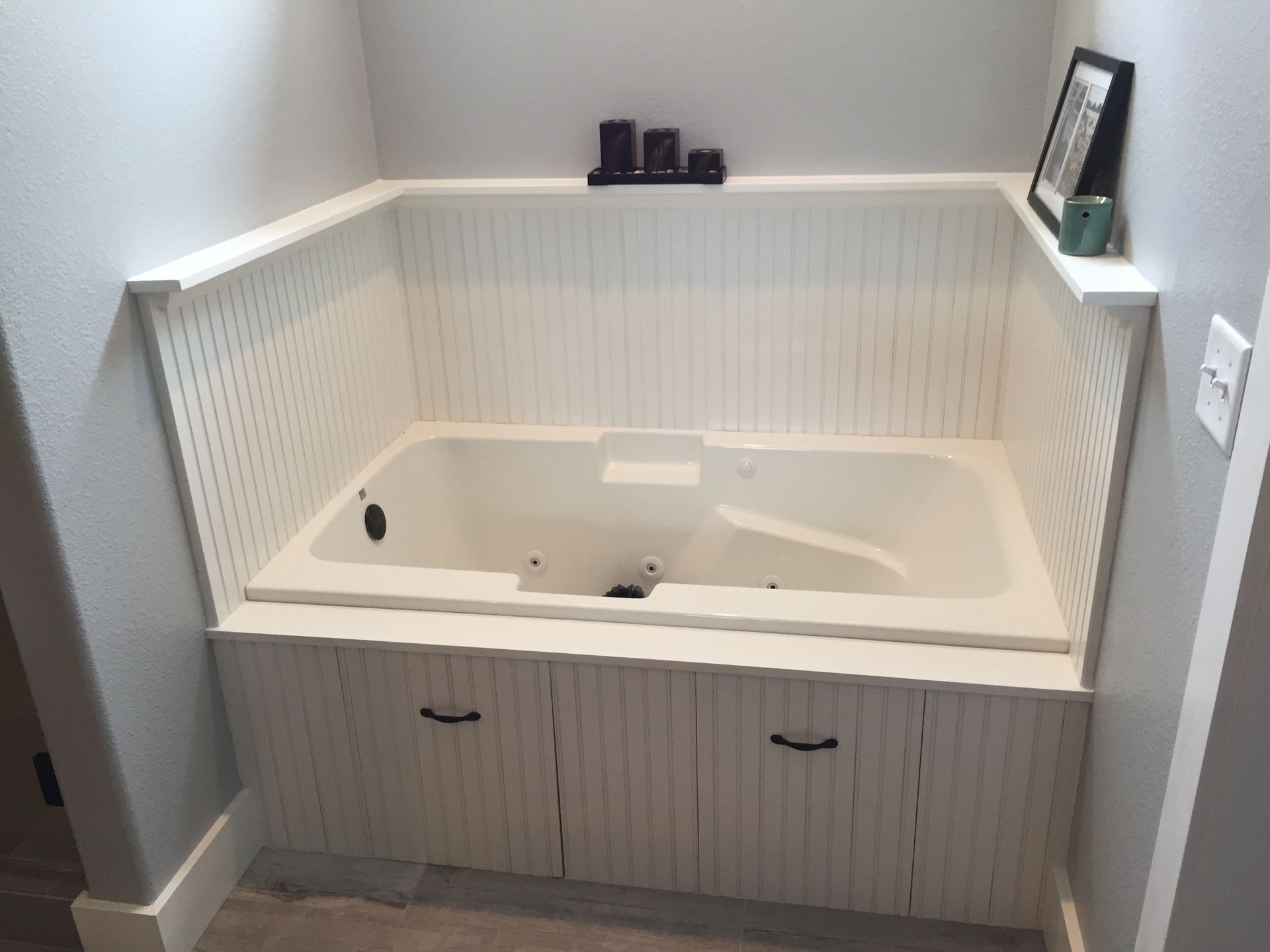White bathroom alcove with a built-in soaking tub and white beadboard paneling