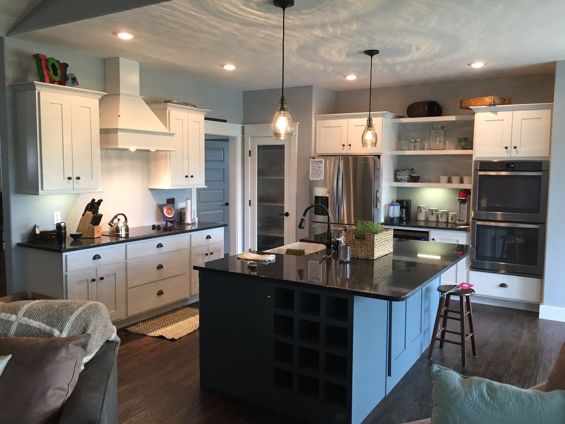 Bright kitchen with white cabinets, dark island, and stainless steel appliances in an open floor plan