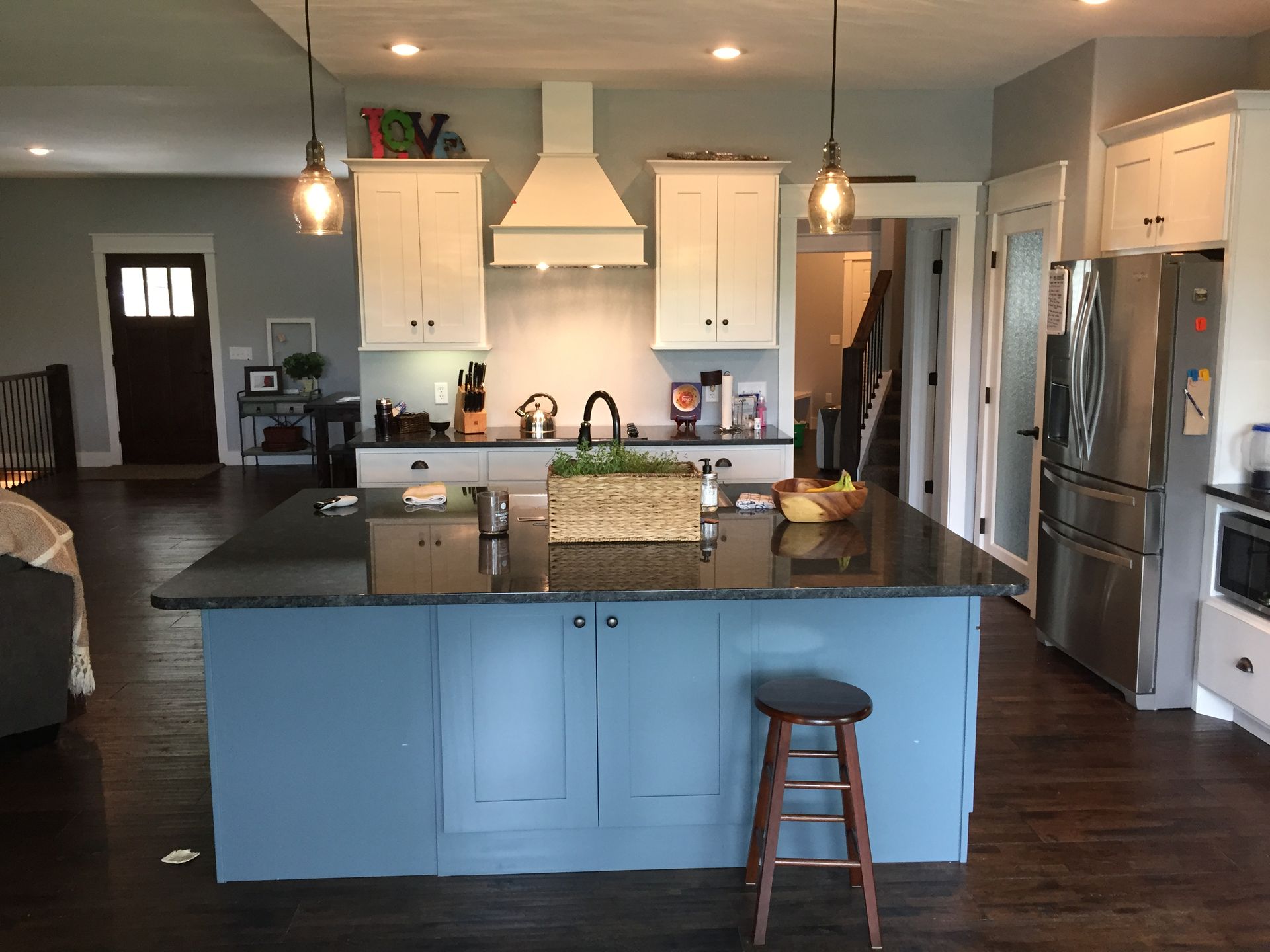 Modern kitchen with blue island, dark countertops, stainless appliances, and pendant lights