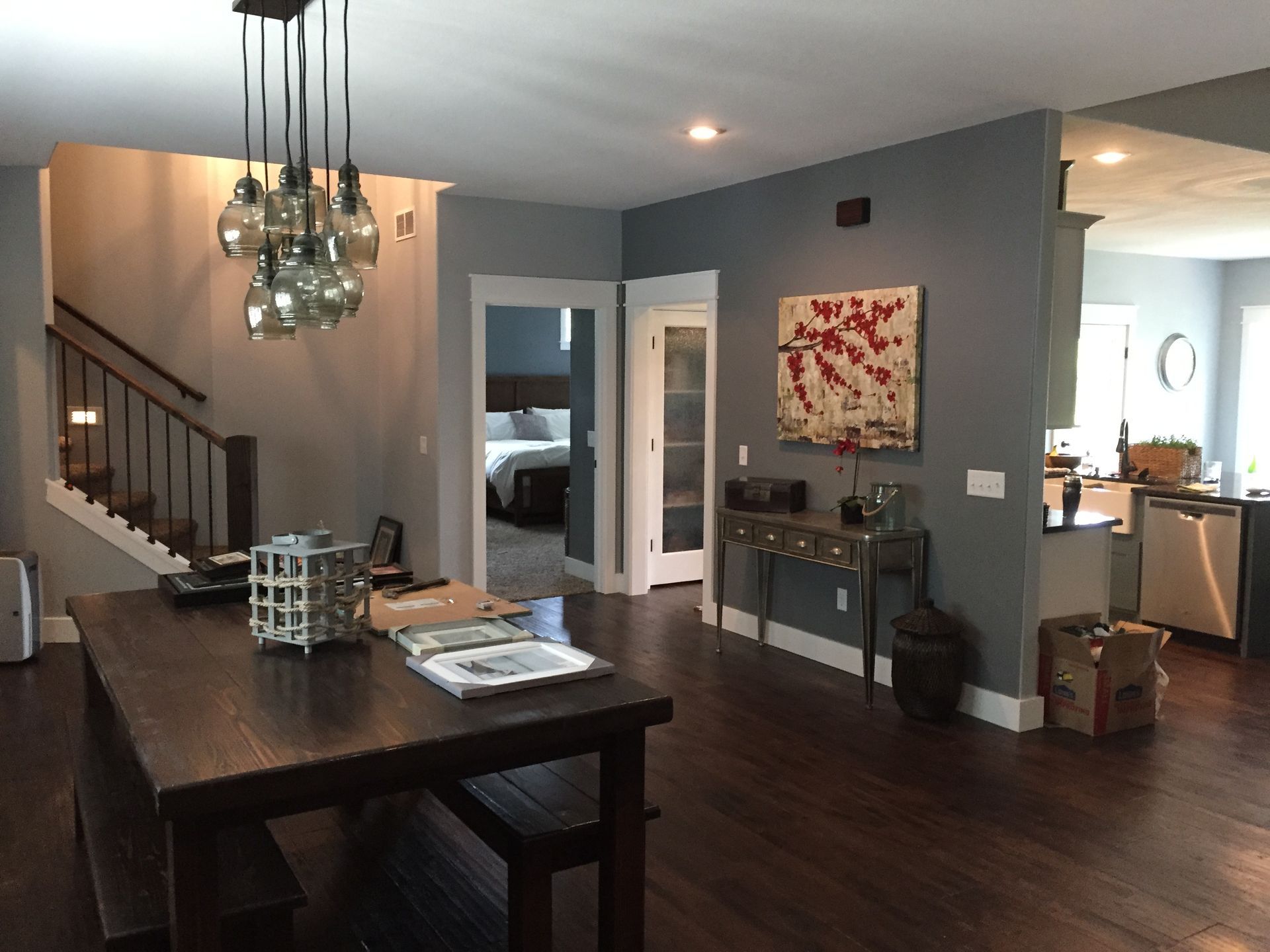 Modern dining and living area with dark wood table, chandelier, staircase, and wall art