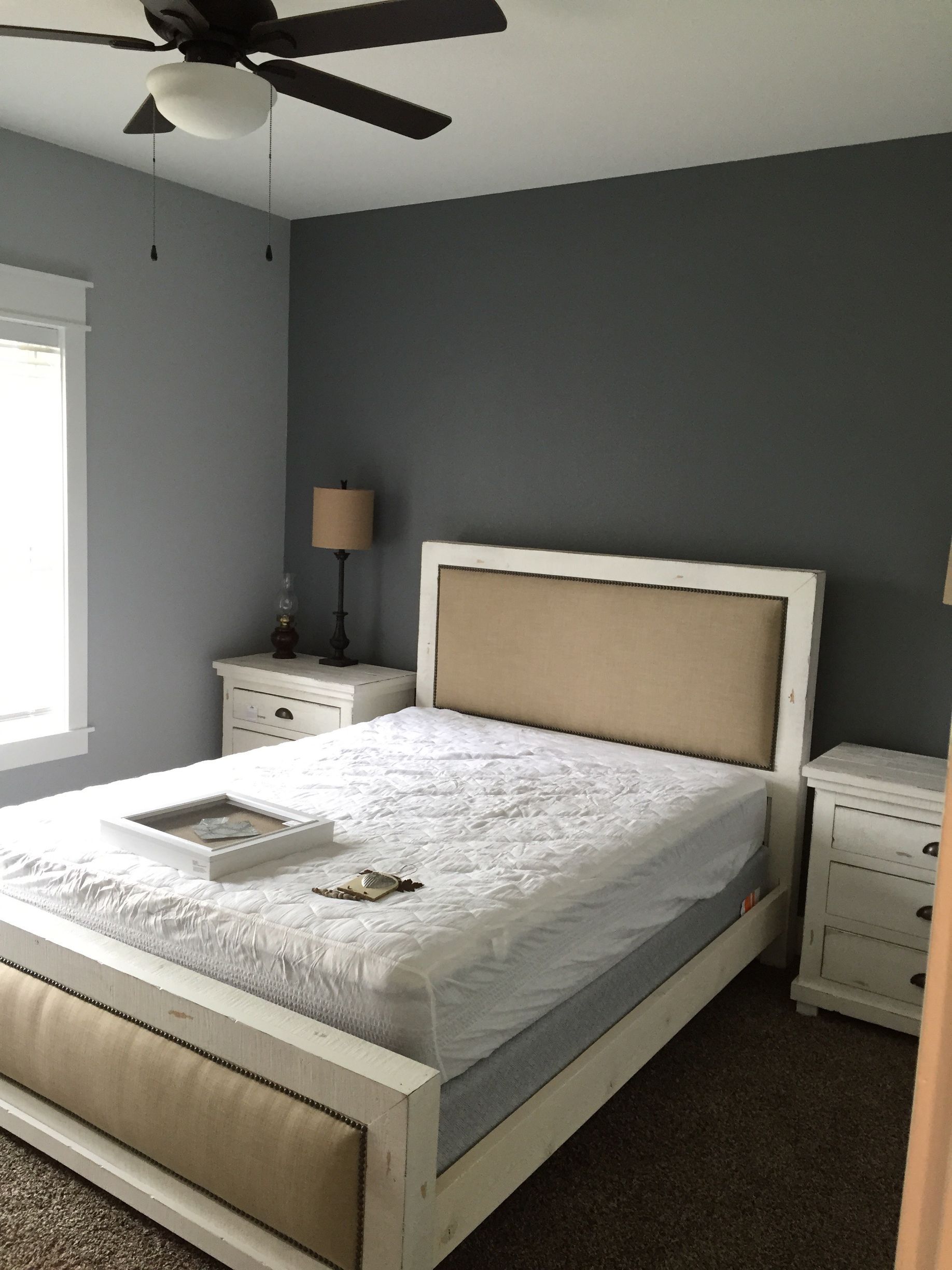 Neat gray bedroom with a white bed, matching nightstands, a floor lamp, and ceiling fan