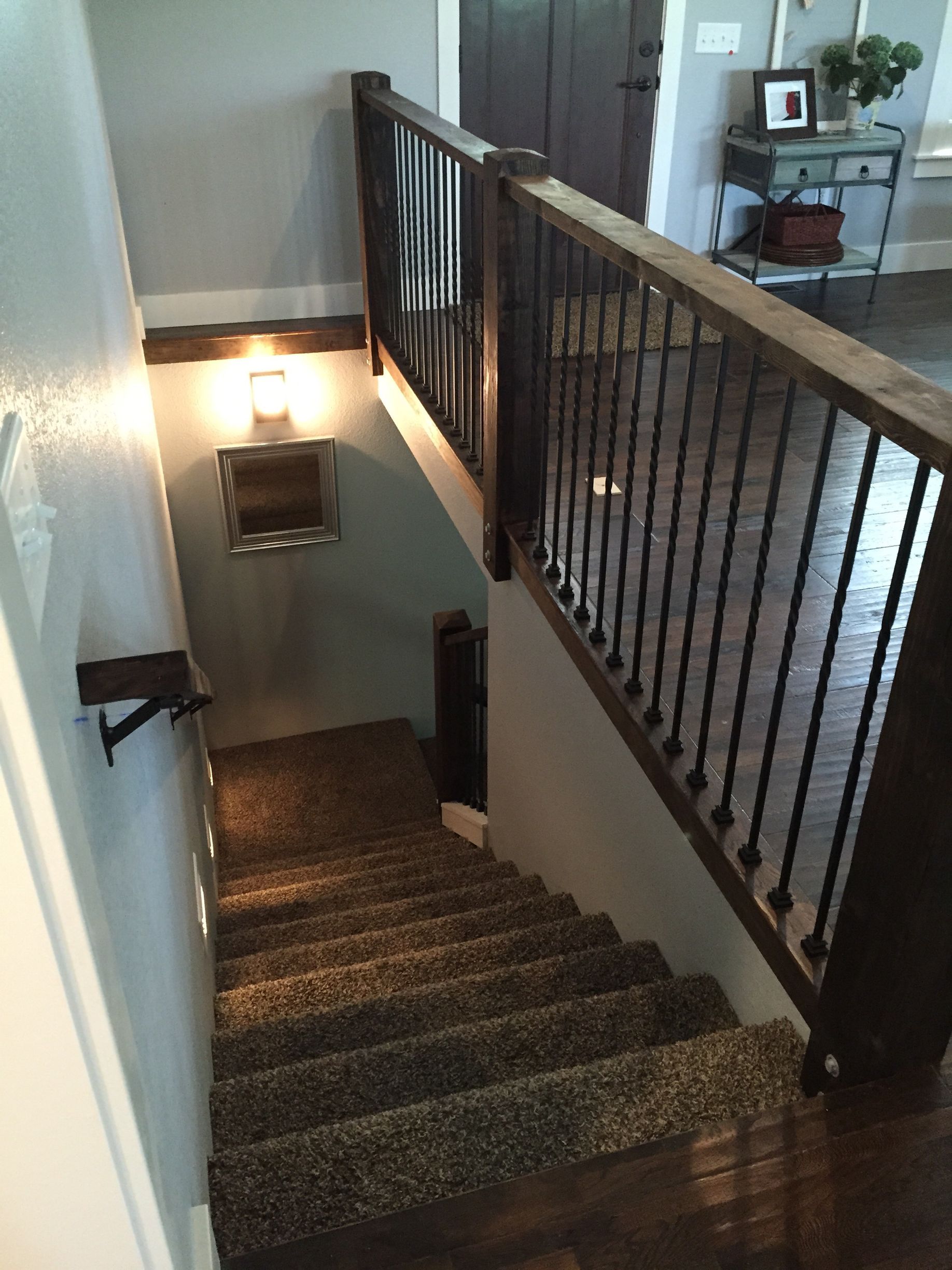 Stairwell with carpeted steps, black railing, and a wall light illuminating the landing