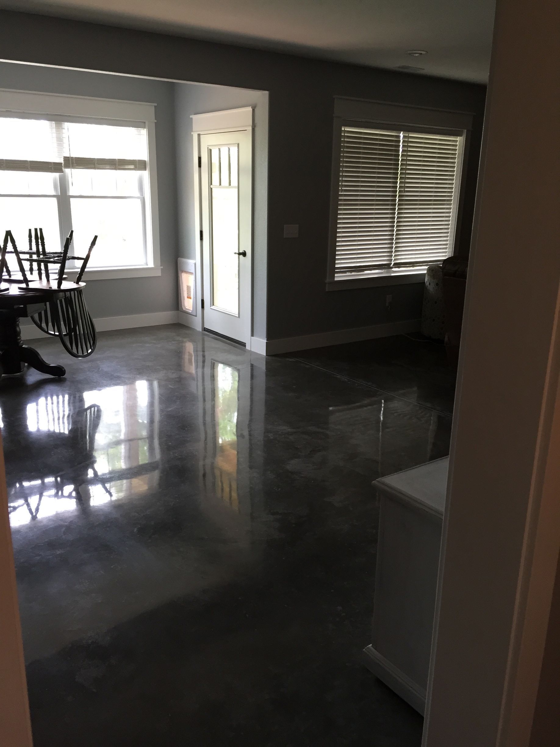 Dim living room with shiny floors, sunlight through windows, and a bicycle near the left wall.