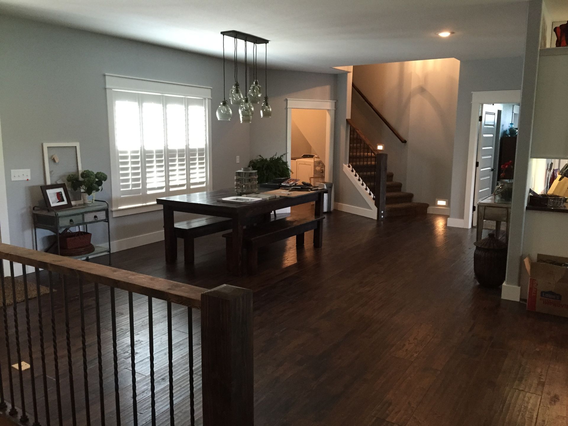 Open-concept dining room with dark wood floors, a pool table, staircase, and bright windows.