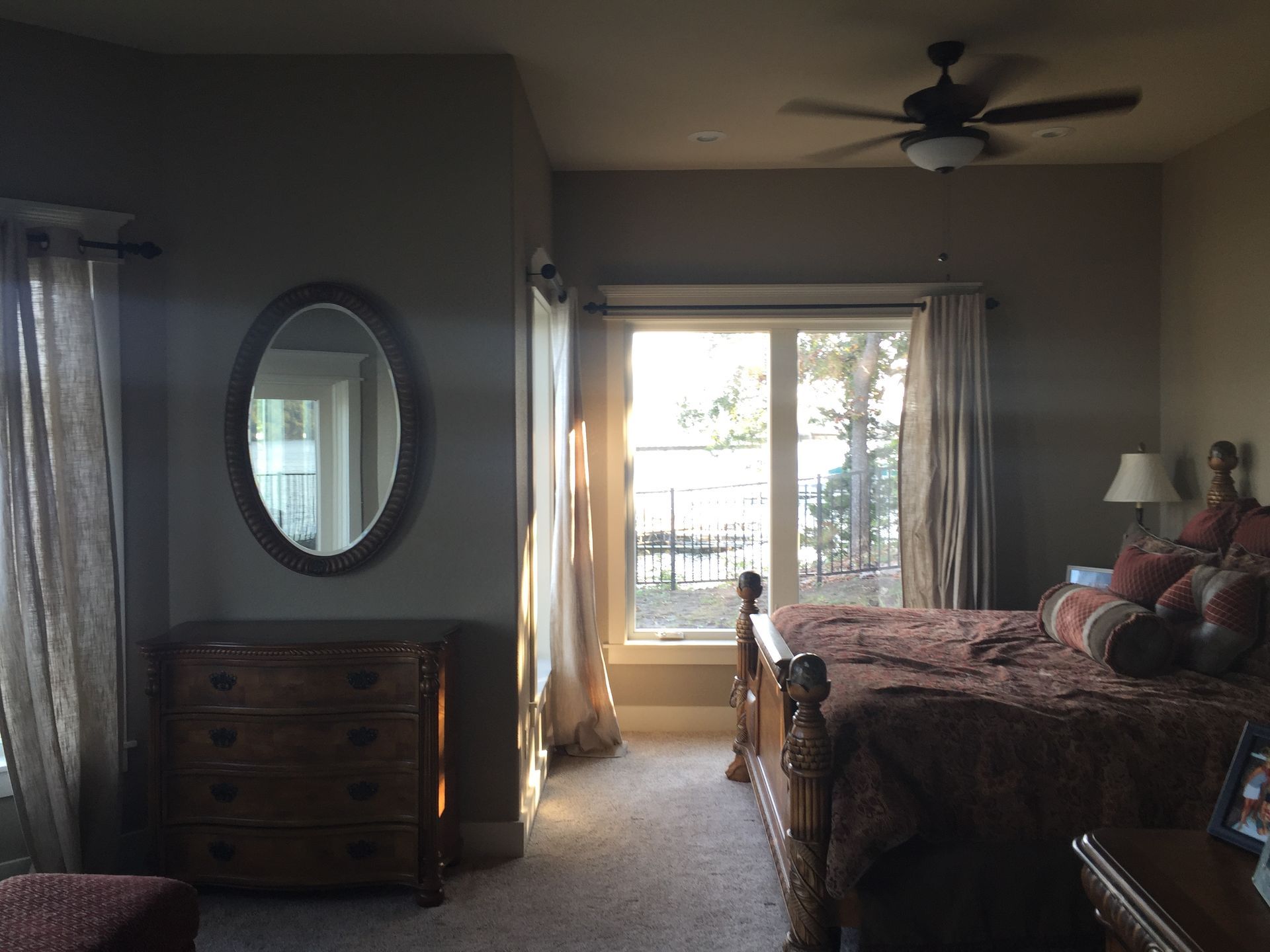 Bedroom with wooden bed, dresser, oval mirror, and sliding doors to a bright patio.