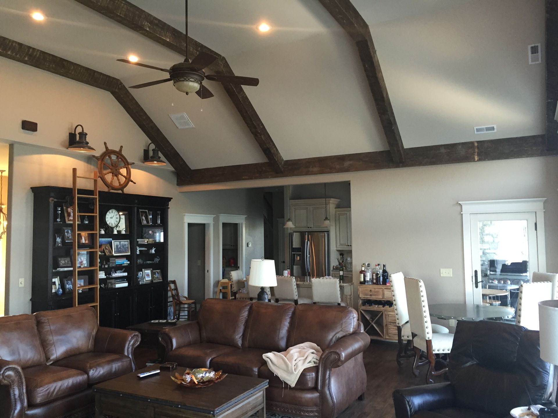 Cozy living room with leather sofas, vaulted ceiling, ceiling fan, and black display cabinet.