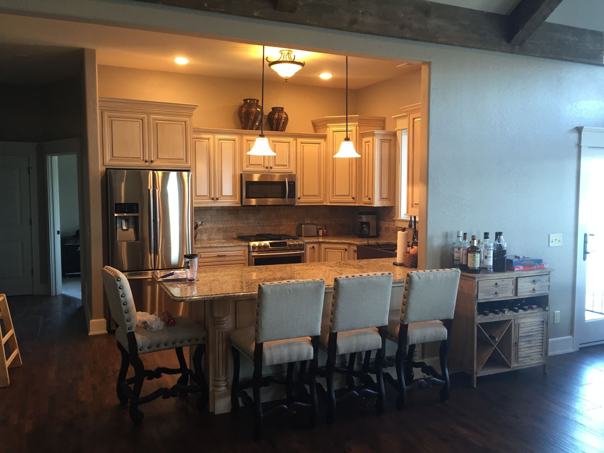 Open kitchen and dining area with white cabinets, stainless fridge, and a long wooden table with chairs.