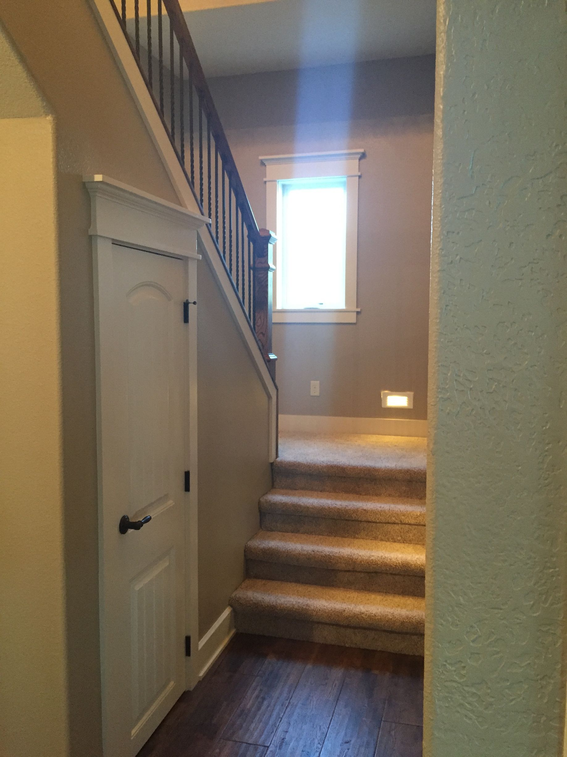 Stairway landing with carpeted steps, a small window, and a closed white door in a hallway