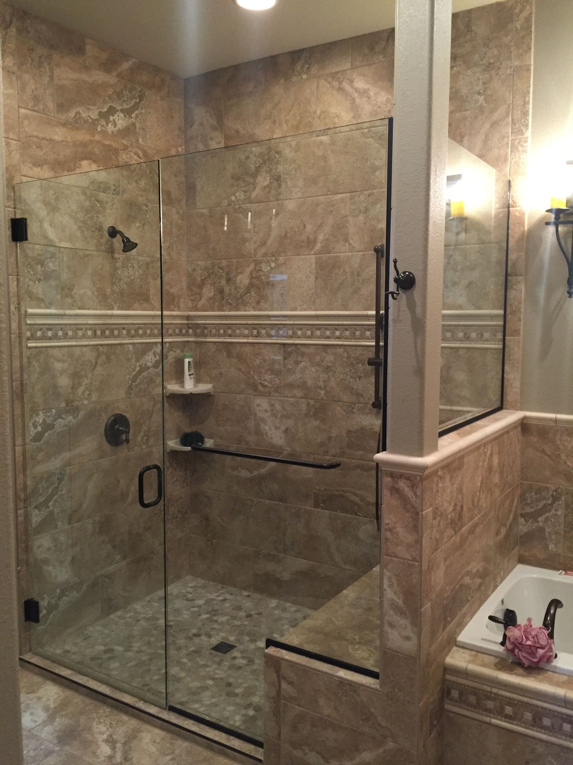Stone-tiled bathroom with glass-enclosed walk-in shower and chrome fixtures