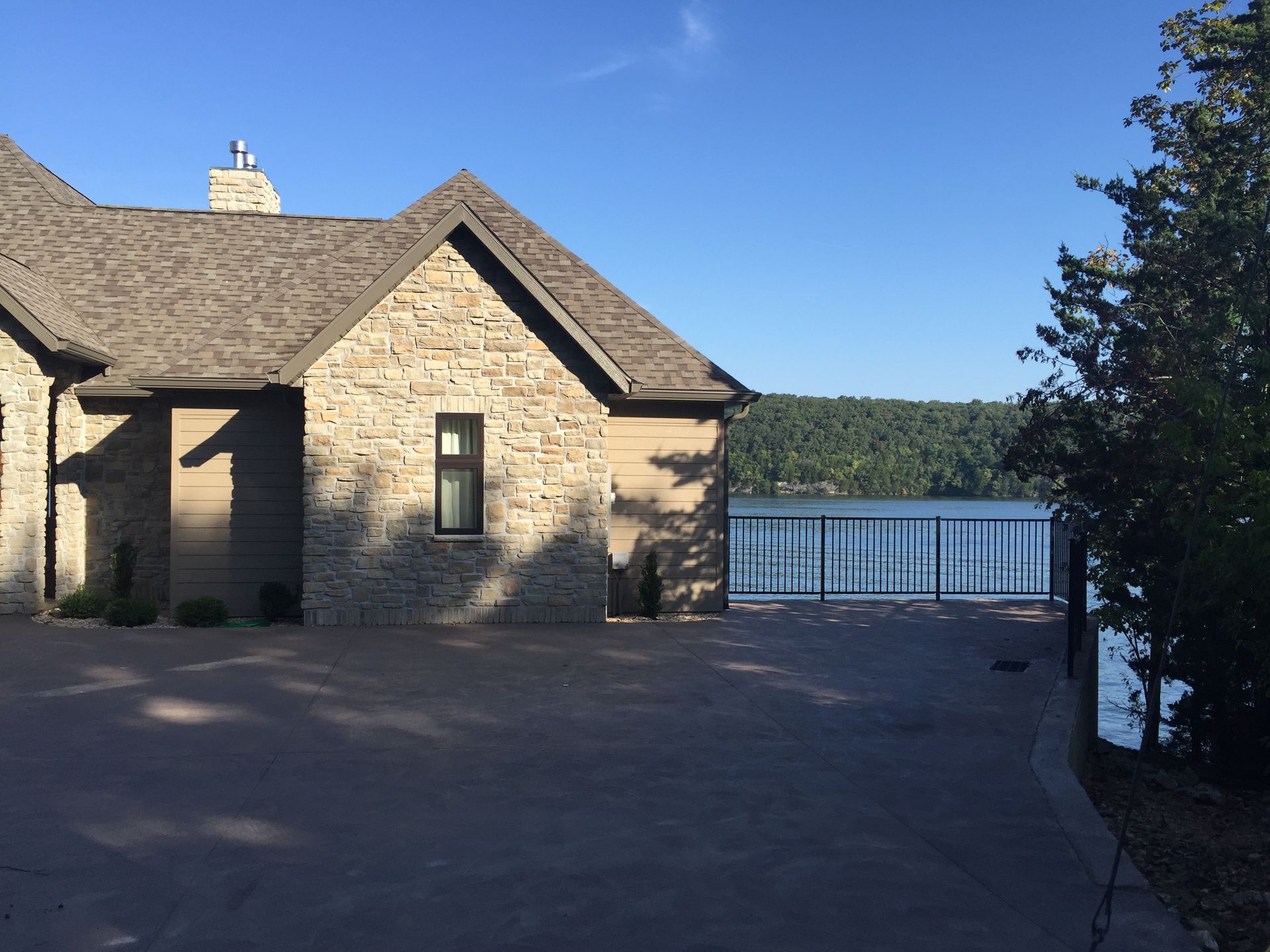 Stone house courtyard overlooking a lake under a clear blue sky