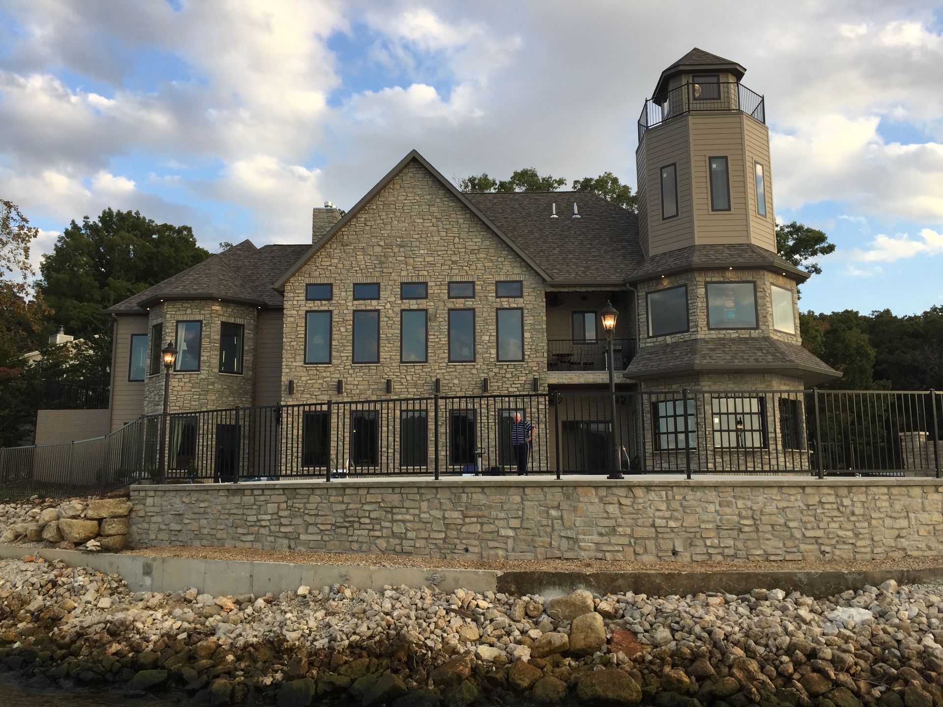 Stone mansion by the water with a tower and stone seawall under a cloudy sky