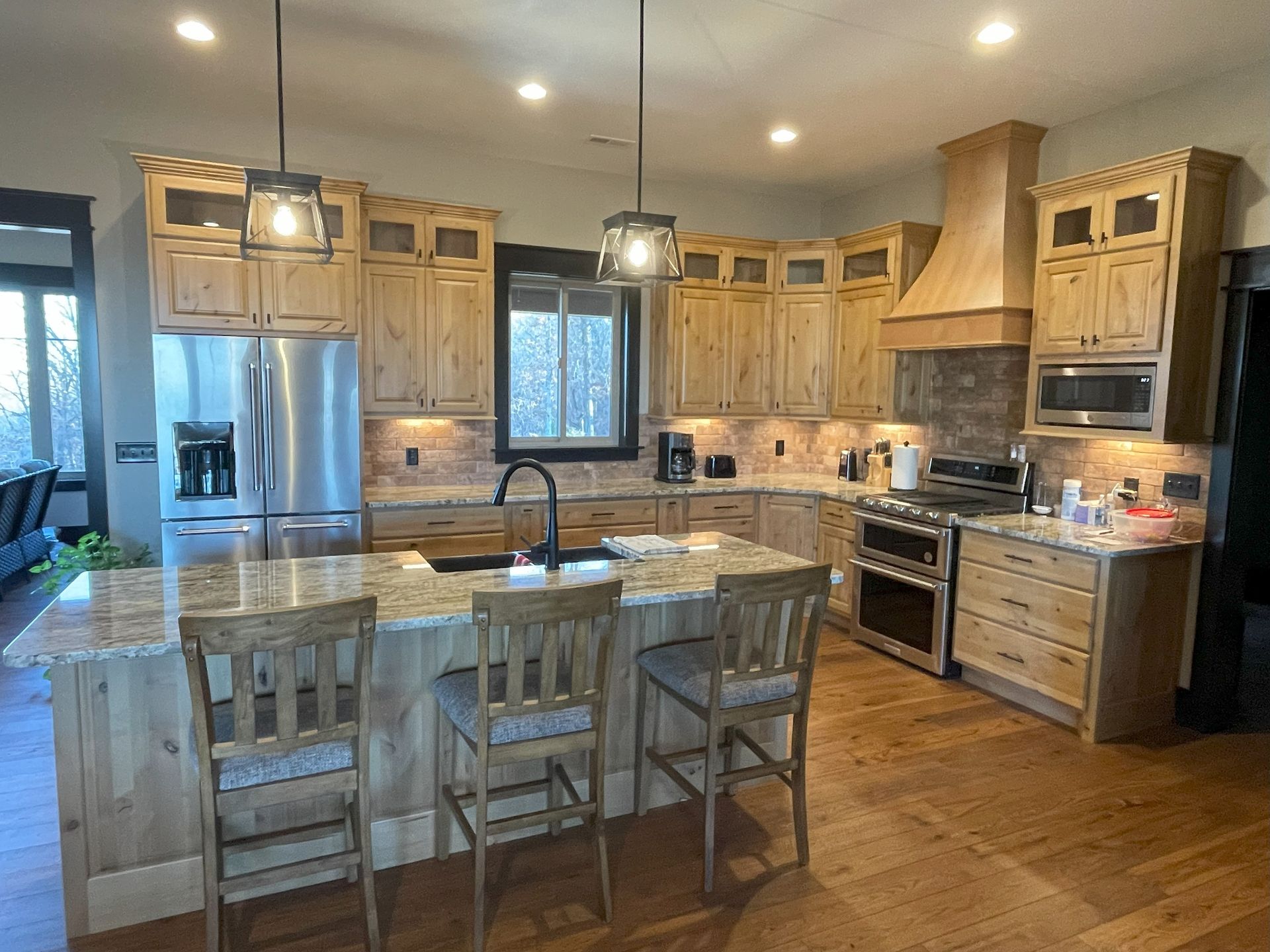Spacious wood kitchen with stainless-steel appliances, island seating, and bright recessed lighting