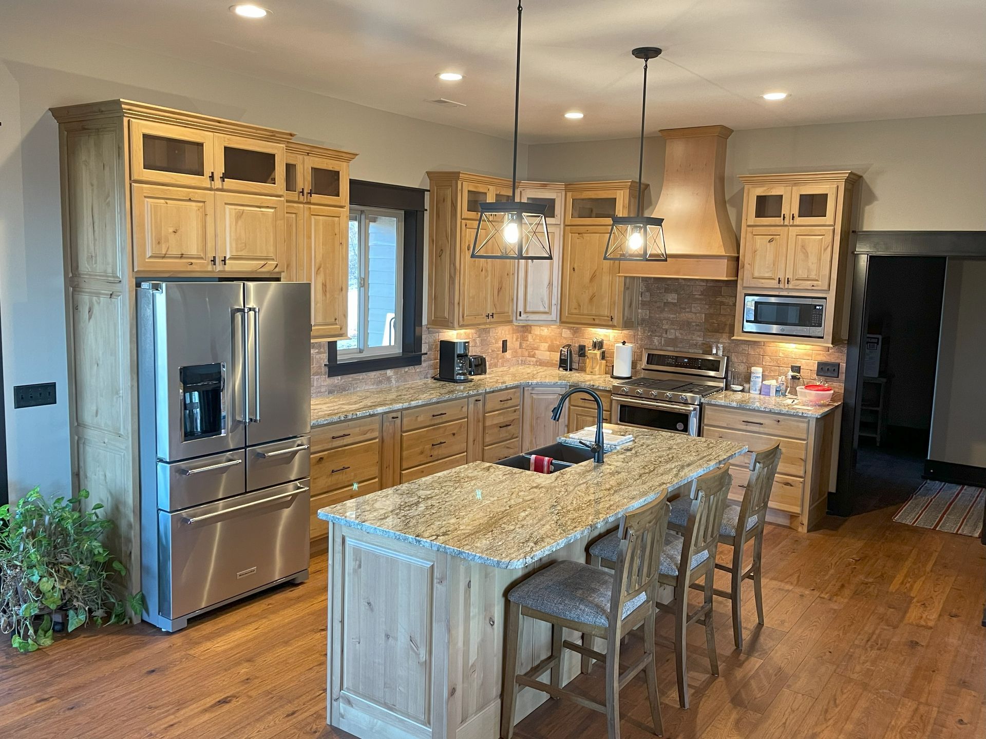 Modern kitchen with wood cabinets, stainless steel appliances, granite island, and hardwood floors