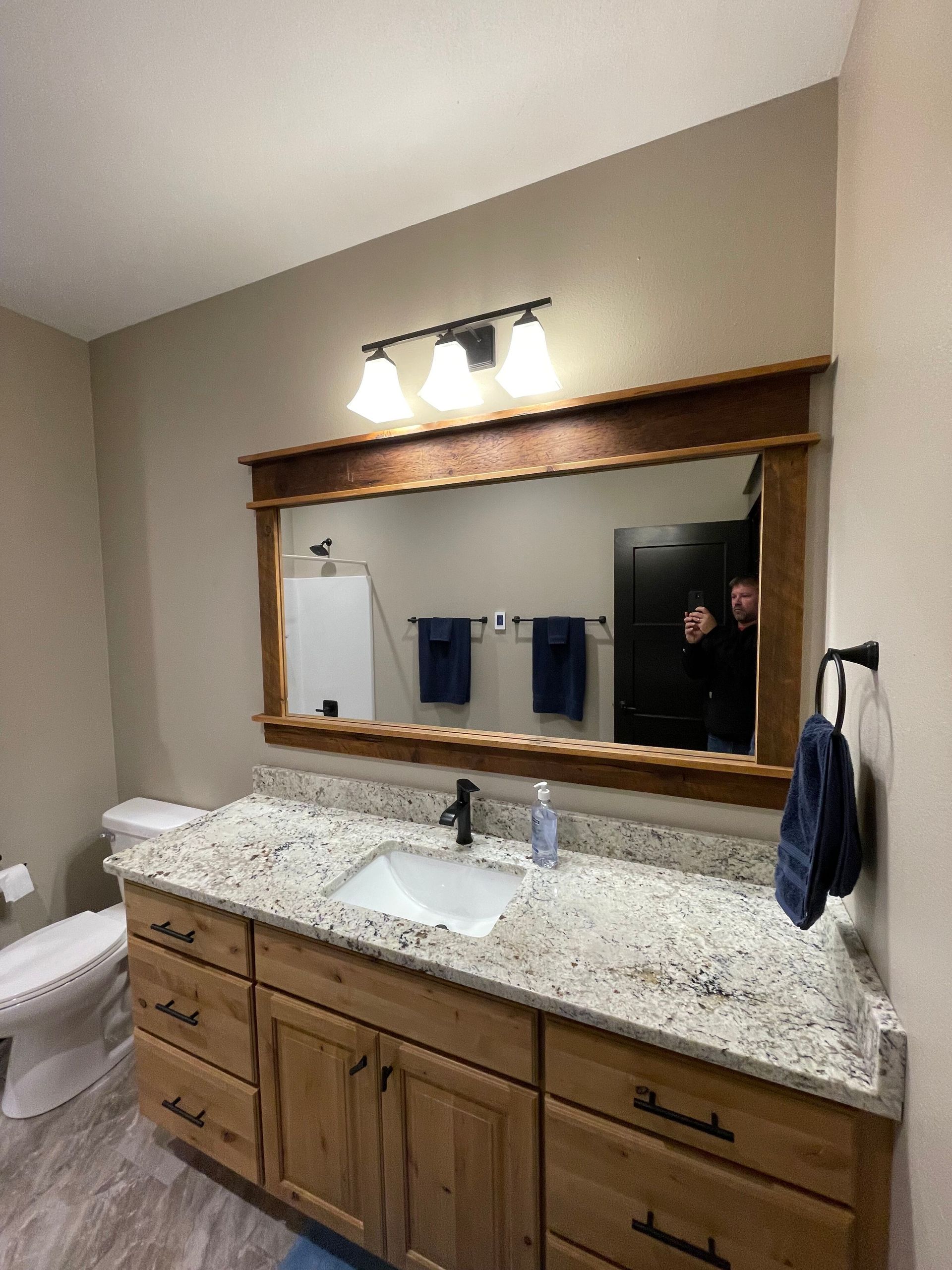 Bathroom vanity with granite countertop, large mirror, and wall light above a sink.