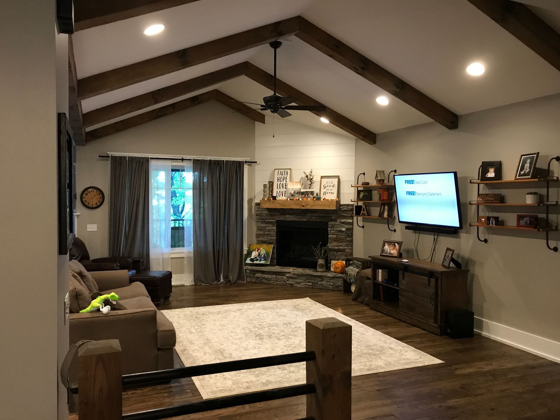 Living room with vaulted ceiling, fireplace, TV, sectional sofa, and large rug