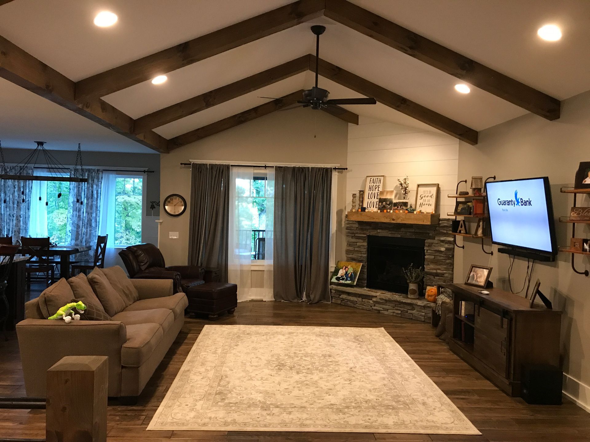 Cozy living room with vaulted wood ceiling, sofa, fireplace, TV, and large beige rug