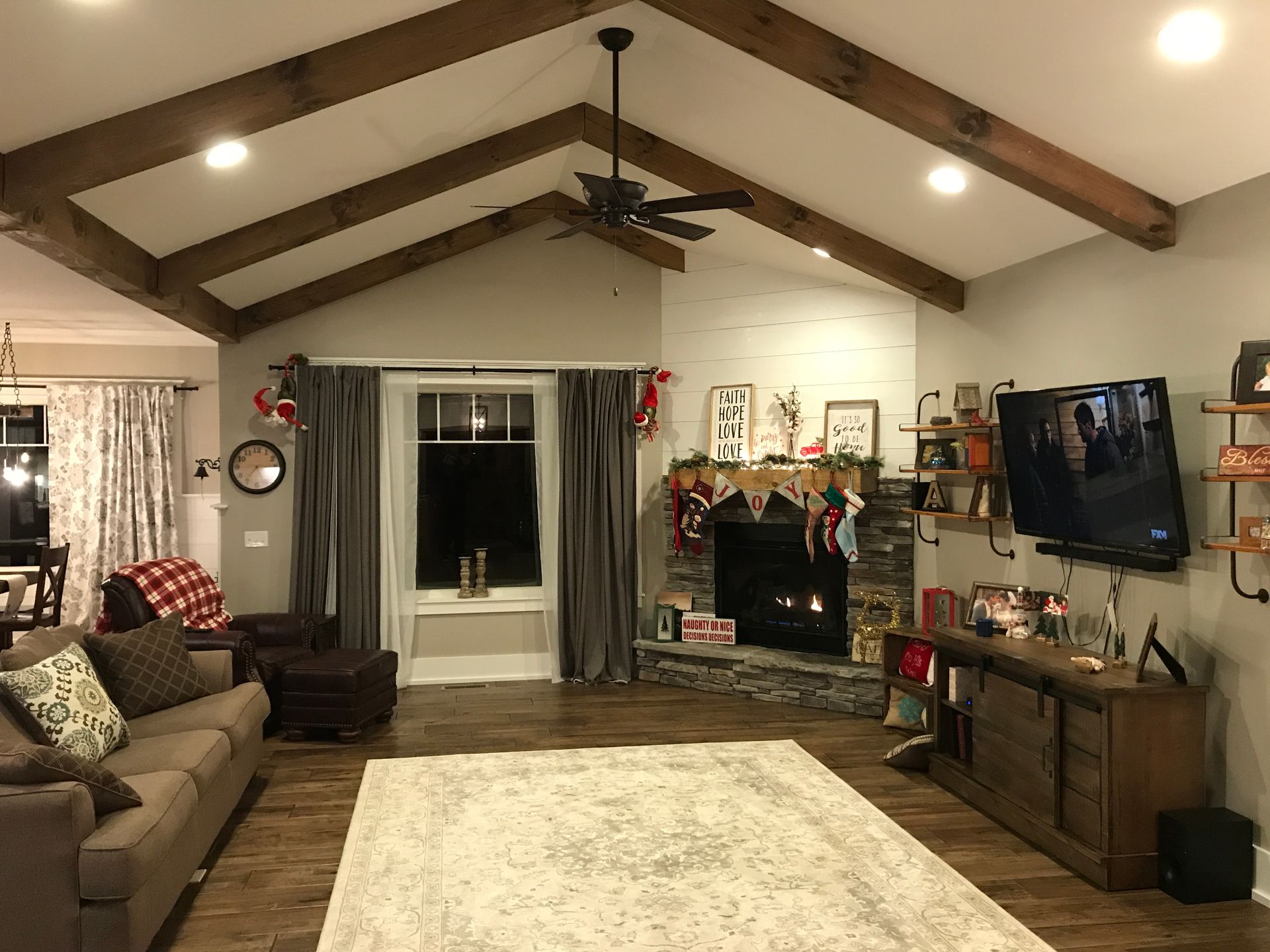 Cozy living room with vaulted ceiling, fireplace, sectional sofa, large TV, and festive holiday decor