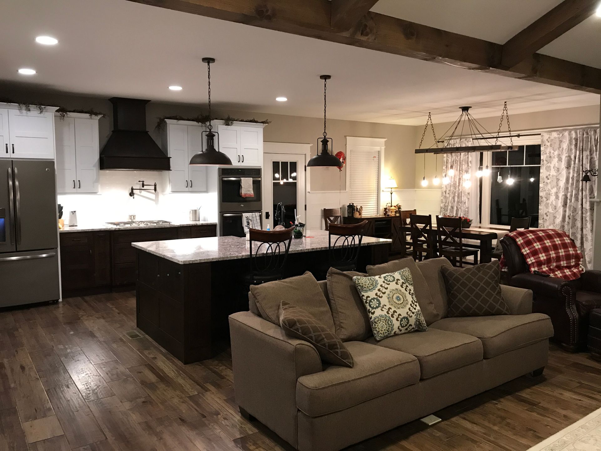 Open-plan kitchen and living room with dark wood floors, island, sofa, and dining table