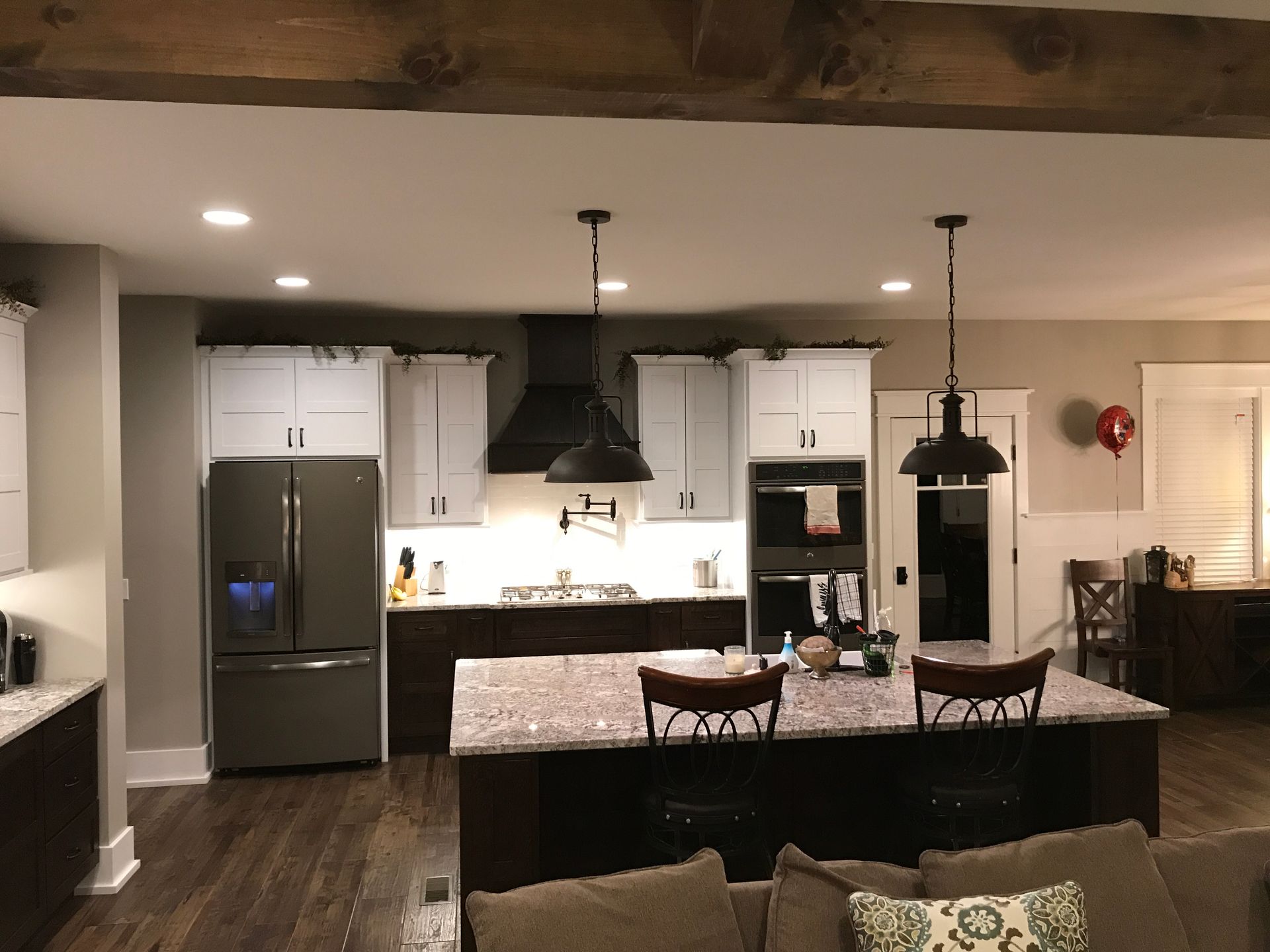 Modern kitchen with stainless steel fridge, white cabinets, island, and pendant lights in a home interior.
