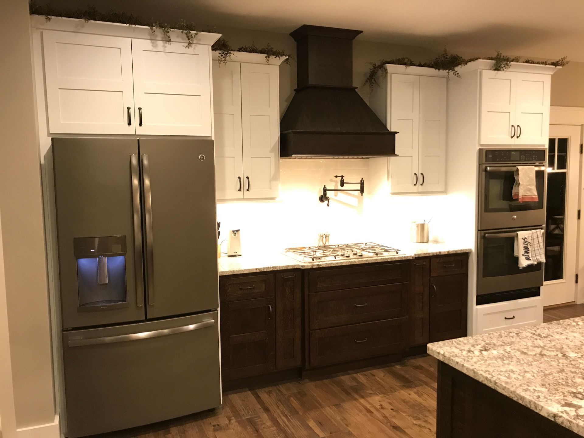 Modern kitchen with stainless steel fridge, dark cabinets, white cabinets, and granite countertops