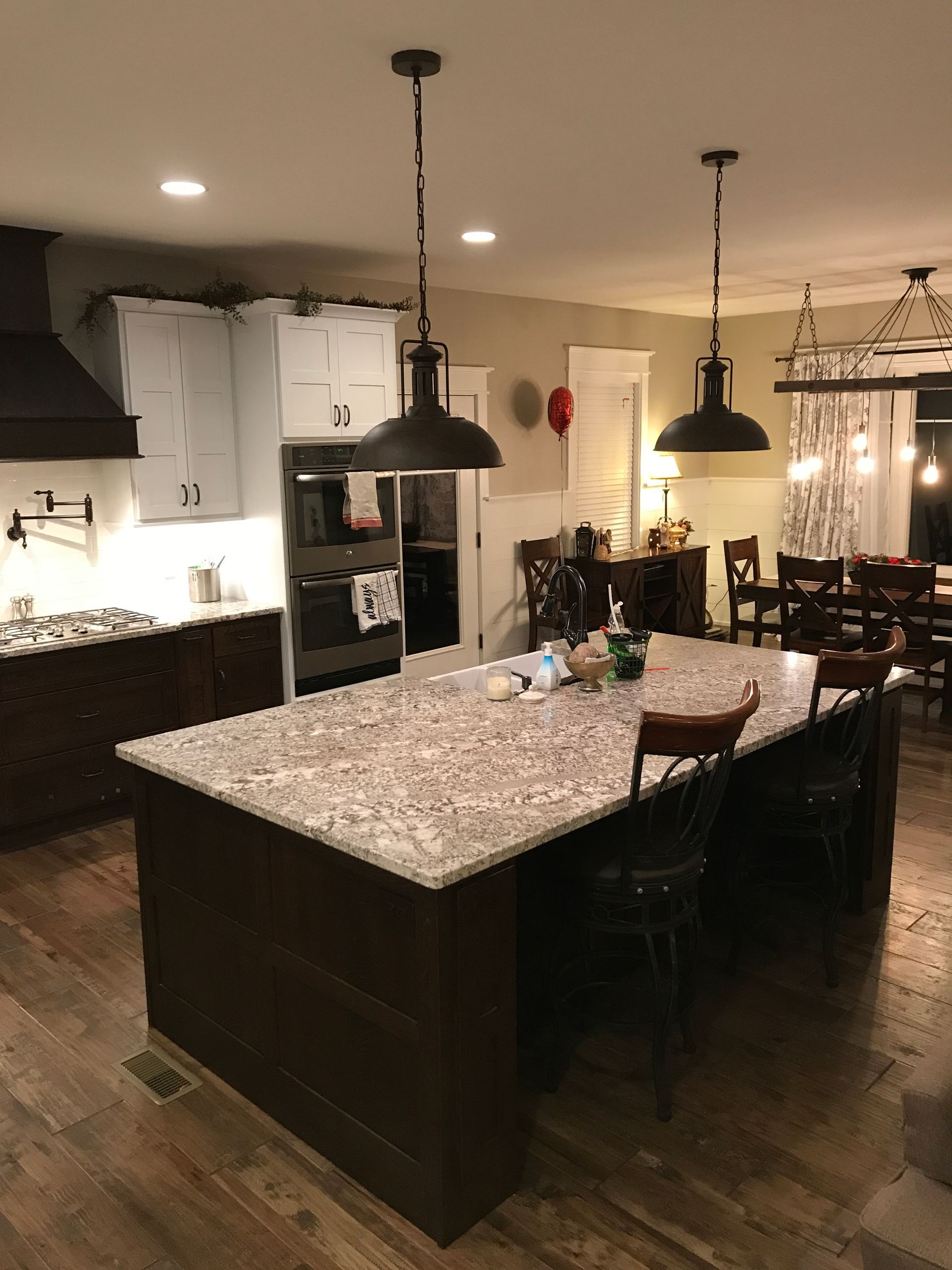 Modern kitchen with granite island, dark cabinets, pendant lights, and hardwood floors