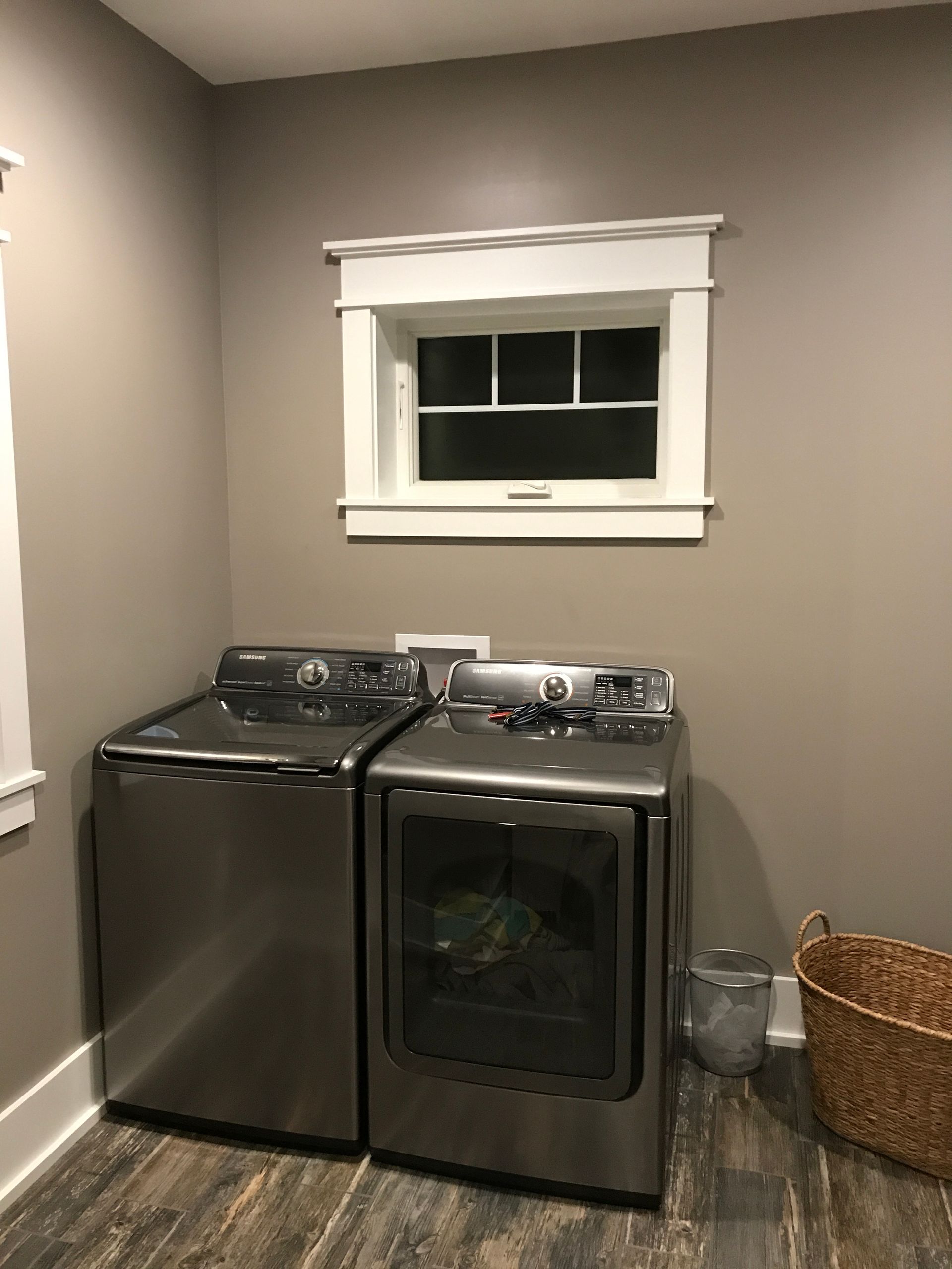 Laundry room with a stainless steel washer and dryer beneath a small window.