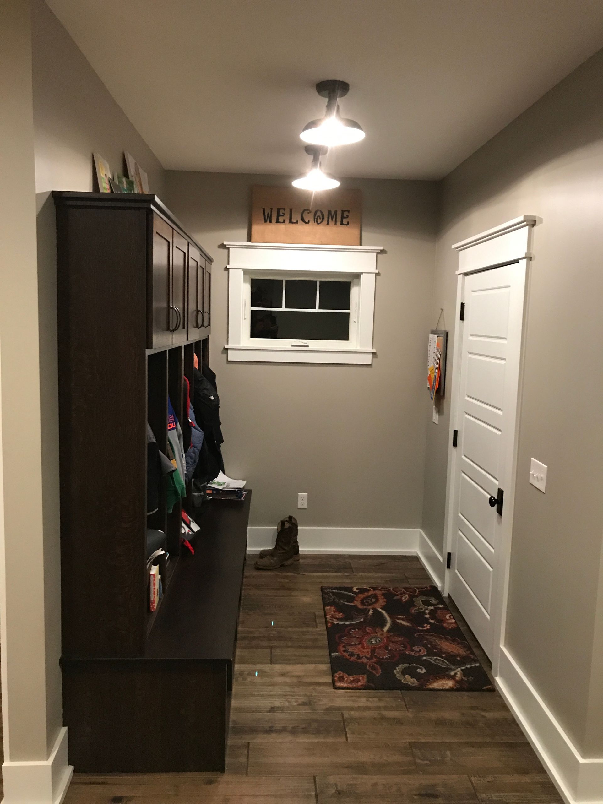 Narrow hallway with gray walls, white doors, coat rack, window, and patterned runner rug under ceiling light