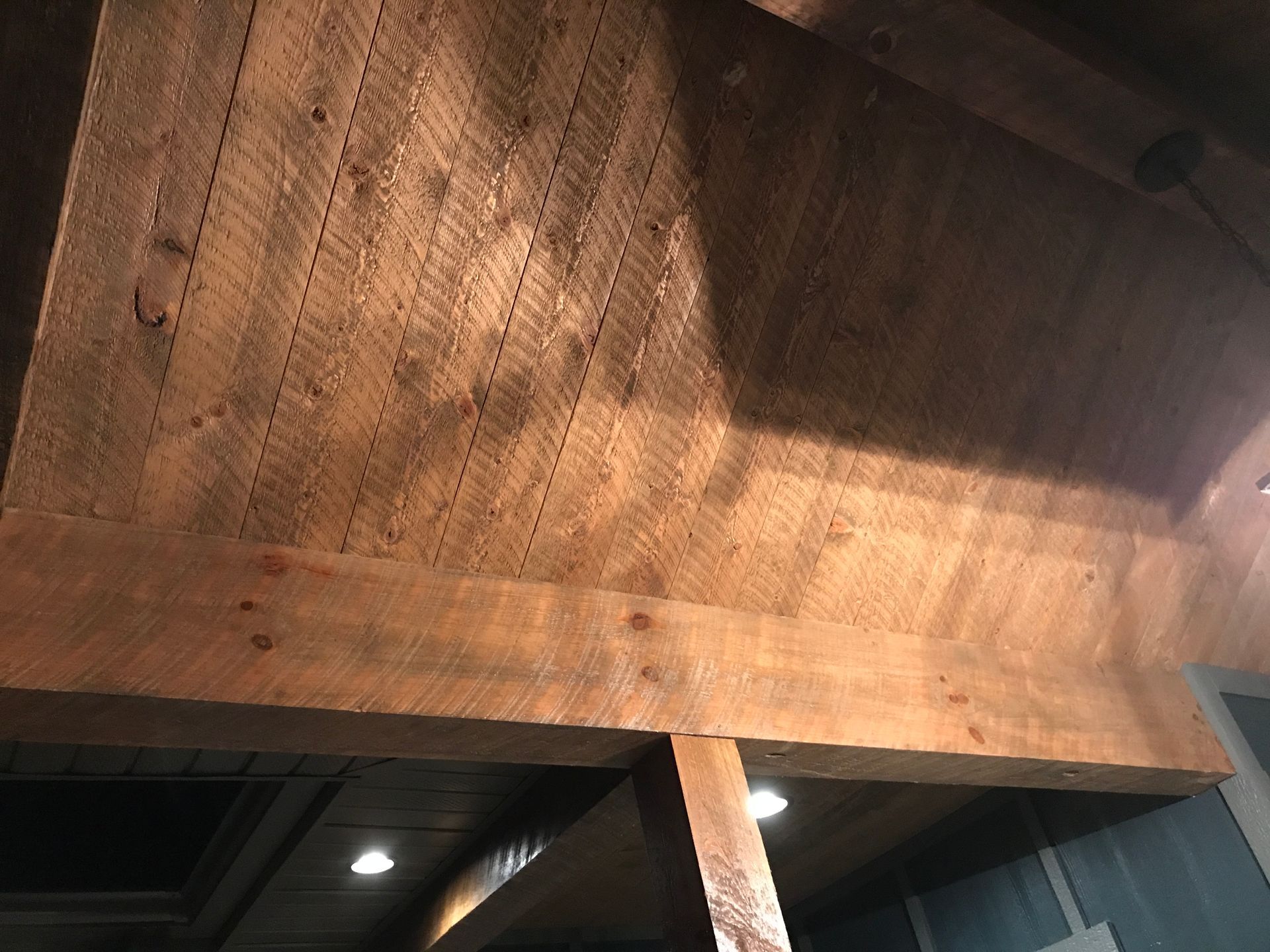 Wooden beams and a ceiling lit by warm light, viewed from below.