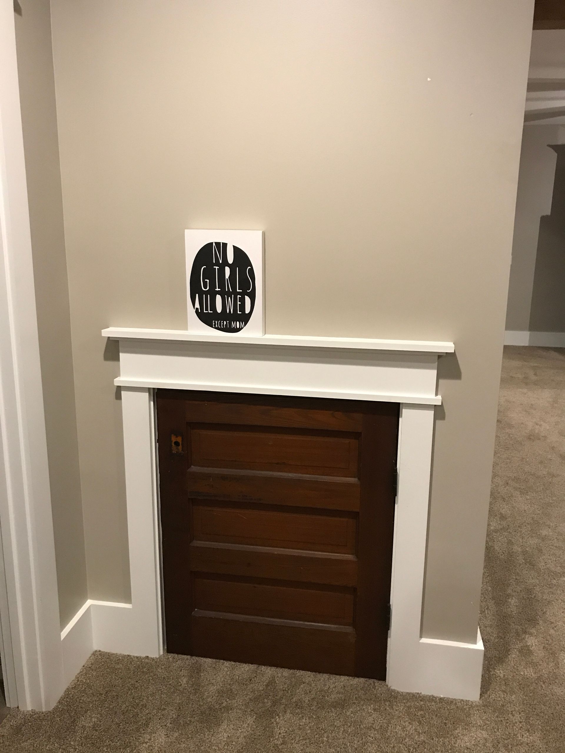 Small brown cabinet under a white mantel in a beige hallway.