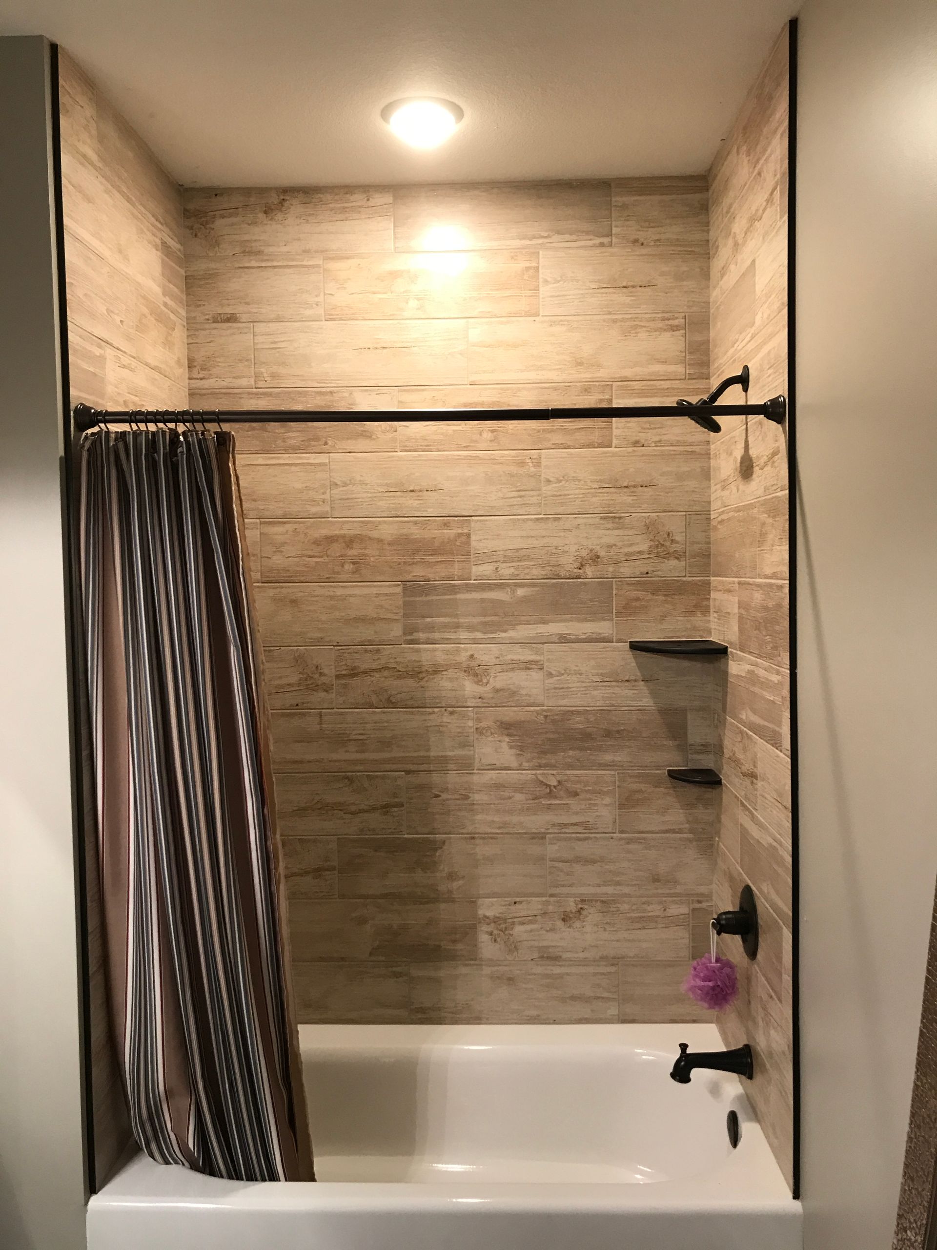 Small bathroom shower with beige tile walls, a curtain, and a bathtub under a ceiling light