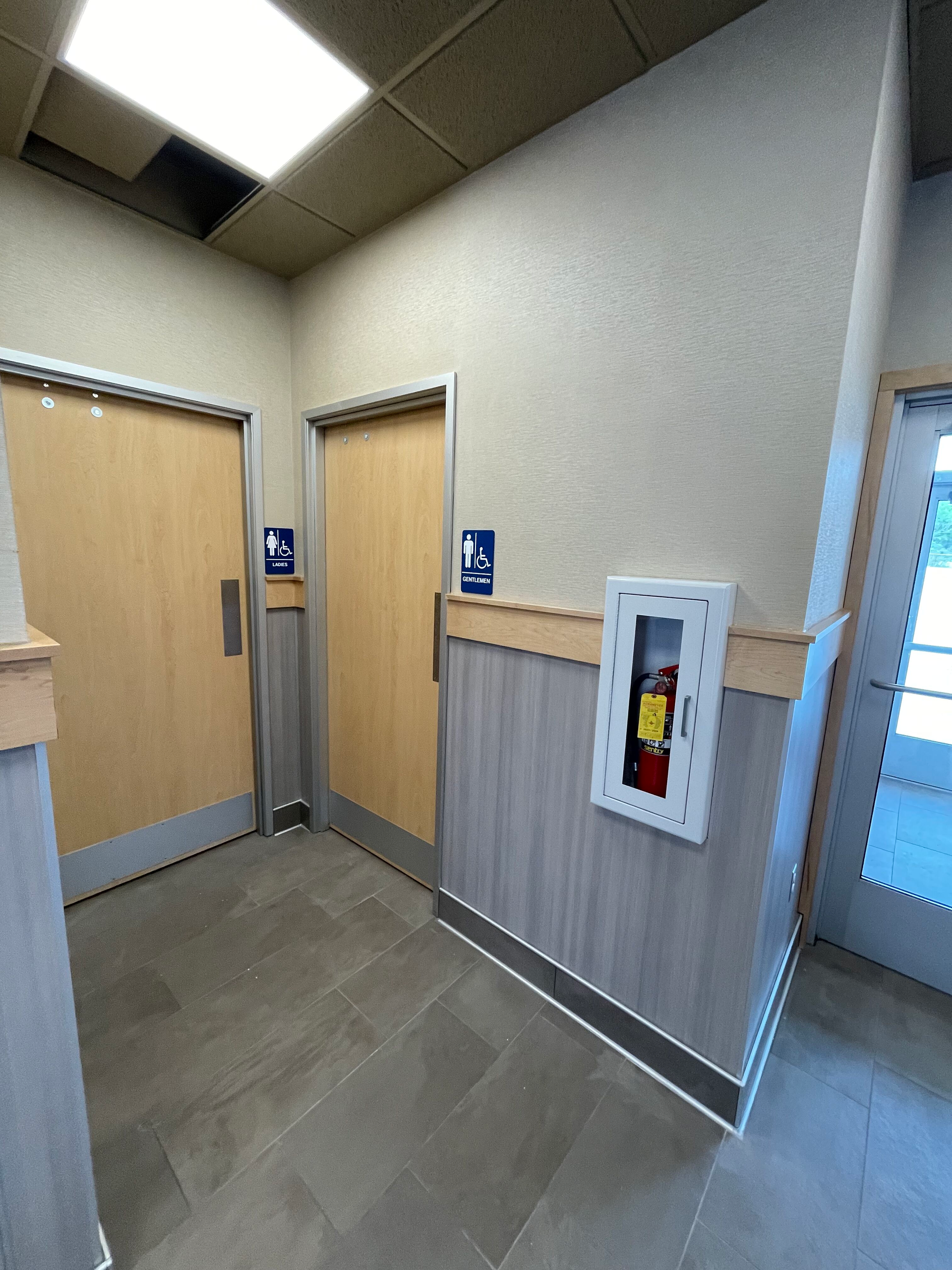 Empty hallway with beige doors, wood paneling, and a wall-mounted fire extinguisher cabinet.