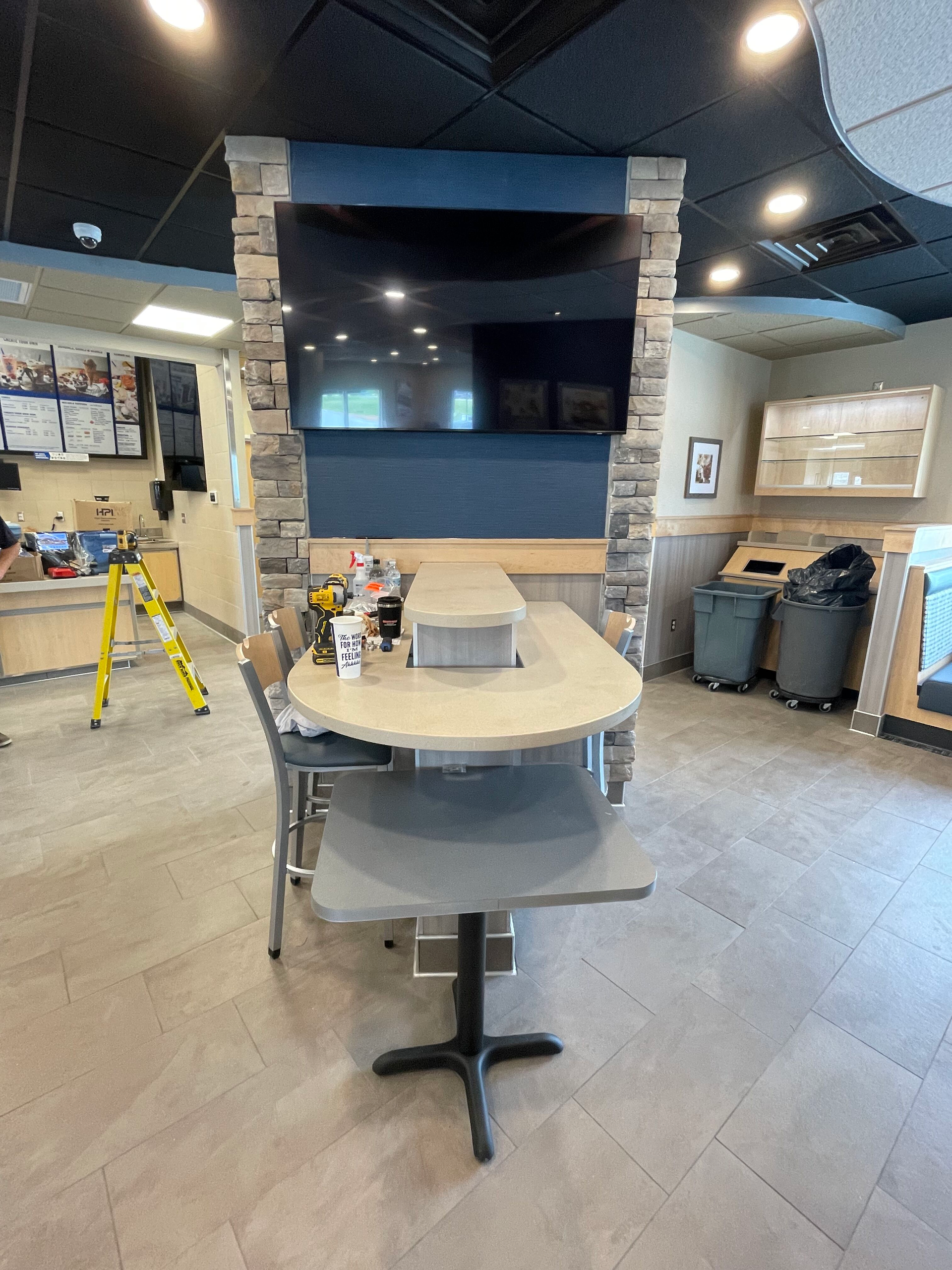 Office lounge with round table, wall-mounted TV, and chairs in a modern workspace